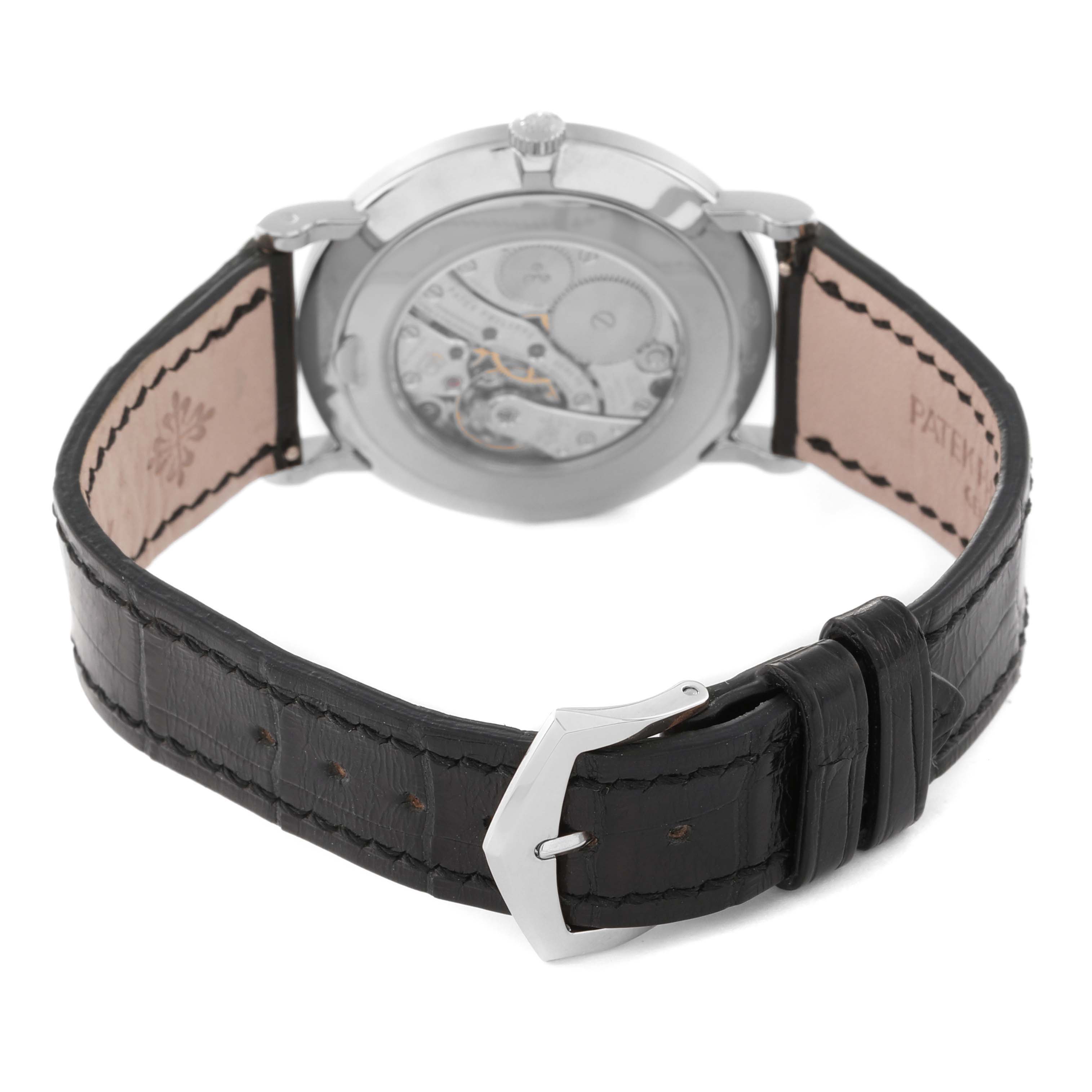 The image shows the back view of a Patek Philippe Calatrava 5116G Men
s White Gold White Dial 5116G Men
s White Gold White Dial watch, highlighting its open case back and black leather strap.