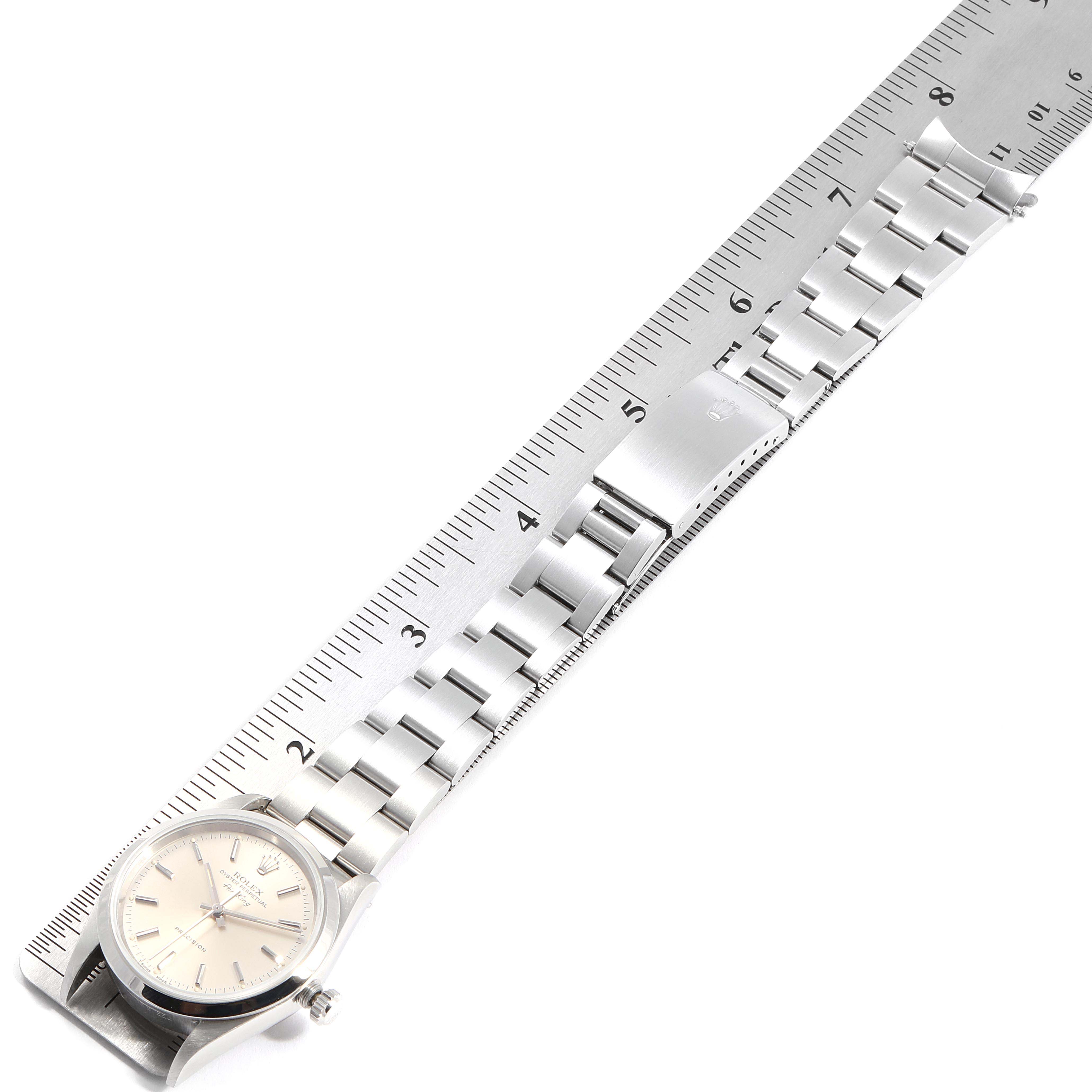 The Rolex Air-King 14000 Men's Stainless Steel Silver Dial 14000 Men's Stainless Steel Silver Dial watch is shown from an overhead angle, with its face, bracelet, and clasp visible next to a ruler for scale.