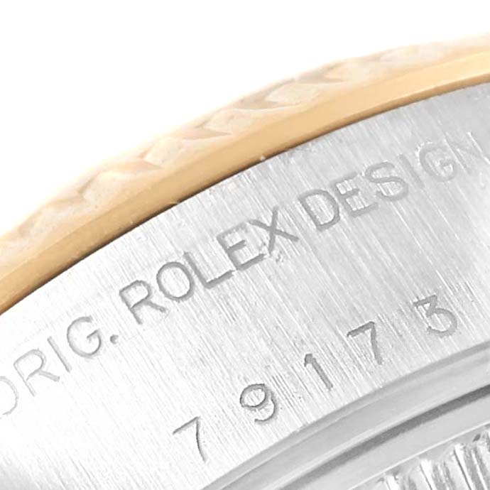 The image shows a close-up of the edge and case back of a Rolex Datejust 79173 Women's Steel and Gold (two tone) Blue Dial 79173 Women's Steel and Gold (two tone) Blue Dial watch with engravings visible.