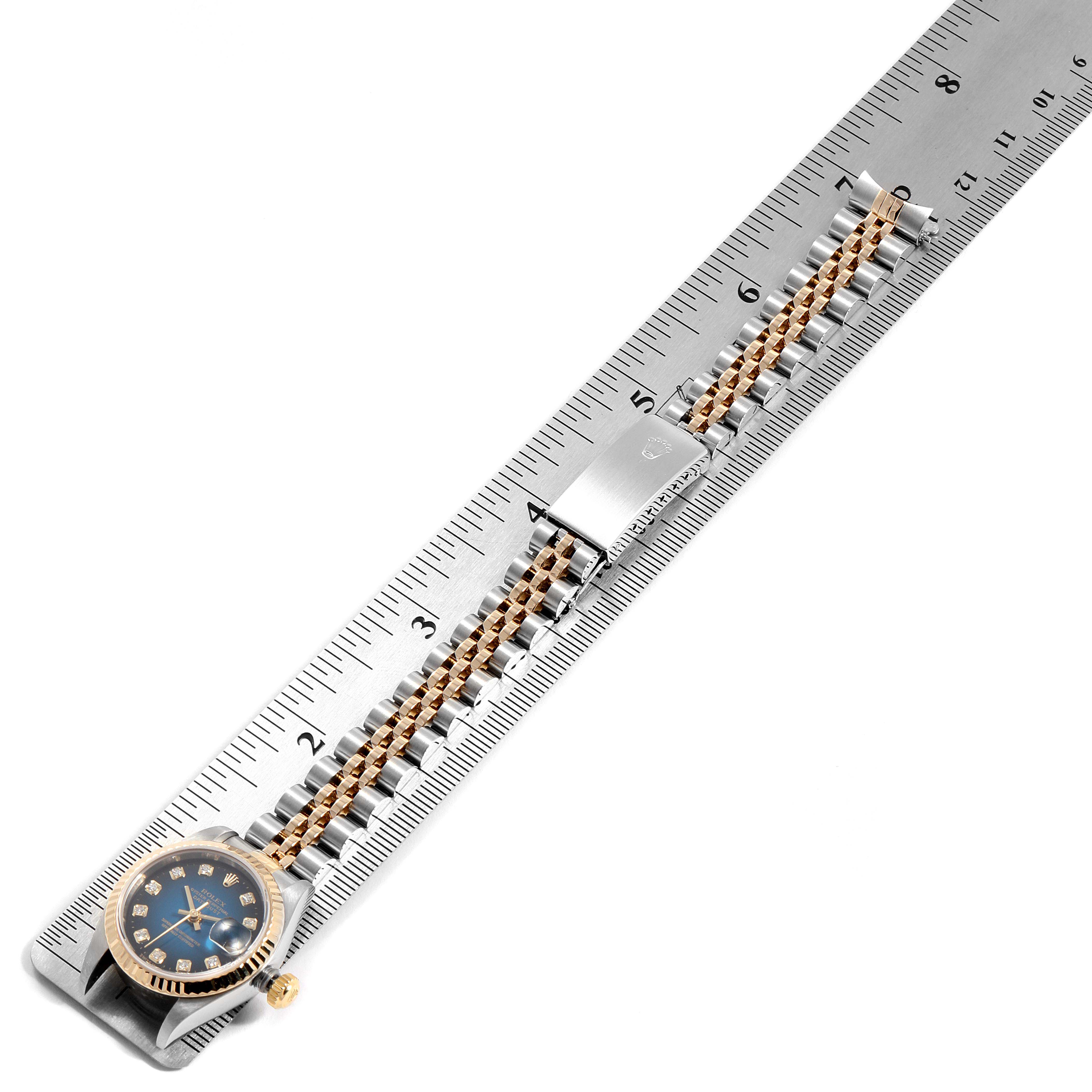 The image shows the Rolex Datejust 79173 Women's Steel and Gold (two tone) Blue Dial 79173 Women's Steel and Gold (two tone) Blue Dial watch placed beside a ruler, showcasing the face, band, and clasp.