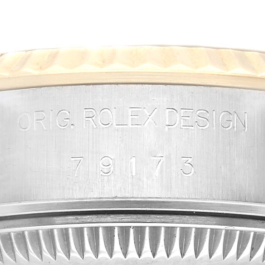 The image shows the engraved case side of a Rolex Datejust 79173 Women's Steel and Gold (two tone) Blue Dial 79173 Women's Steel and Gold (two tone) Blue Dial watch, including part of the fluted bezel and case serial number.
