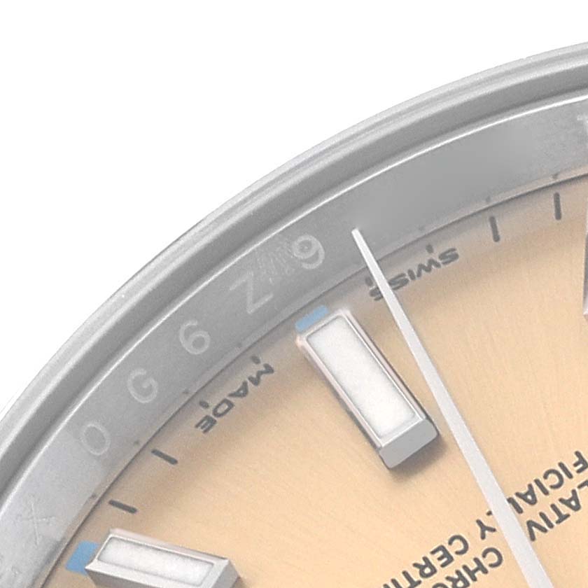 The image shows a close-up of the upper-left portion of the dial and bezel of a Rolex Oyster Perpetual 114200 Men's Stainless Steel Champagne Dial 114200 Men's Stainless Steel Champagne Dial watch.
