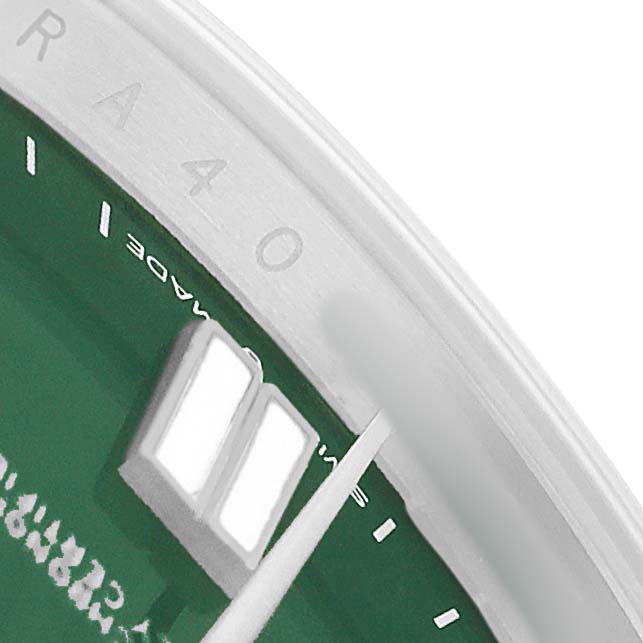 The image shows a close-up of the Rolex Oyster Perpetual 124300-0005 Men's Stainless Steel Green Dial watch dial and bezel with part of the hour markers and hands visible.