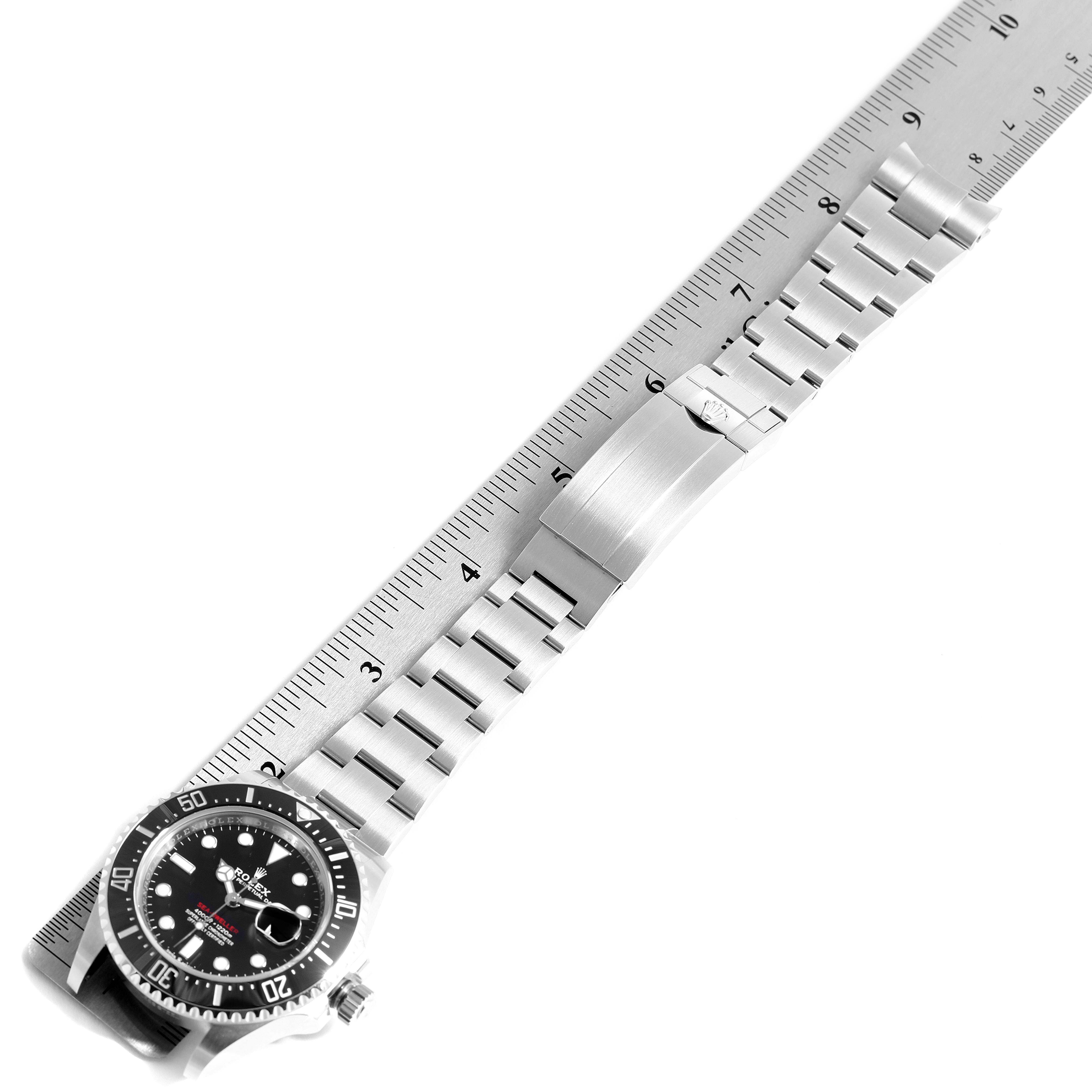 This image shows the front view of the Rolex Sea-Dweller 126600 Men
s Stainless Steel Black Dial 126600 Men
s Stainless Steel Black Dial watch, including the dial, bezel, bracelet, and clasp against a ruler.