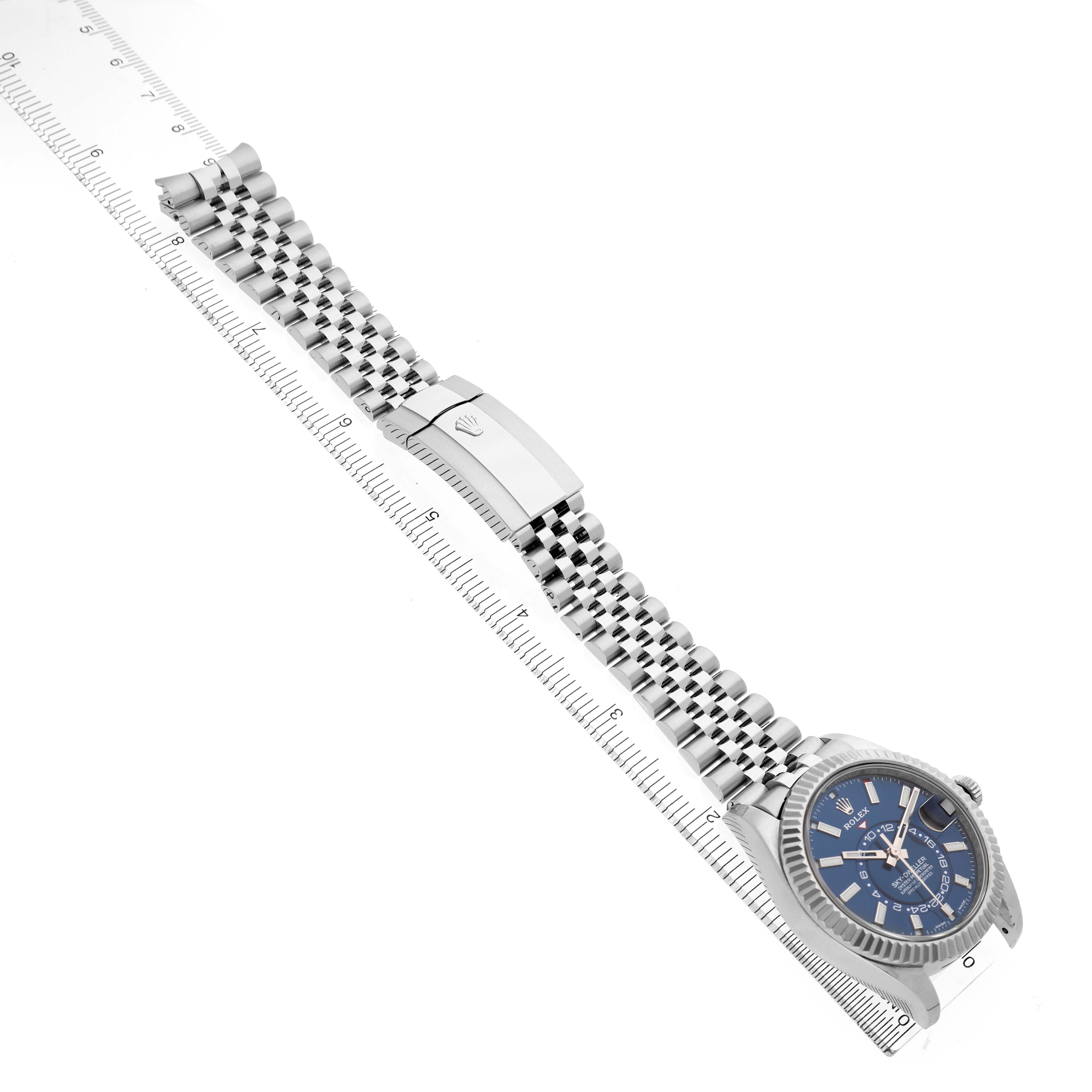 The Rolex Sky-Dweller 336934 Men's Stainless Steel Blue Dial is shown at a top-down angle, highlighting the watch face, bracelet, and clasp against a ruler for scale.