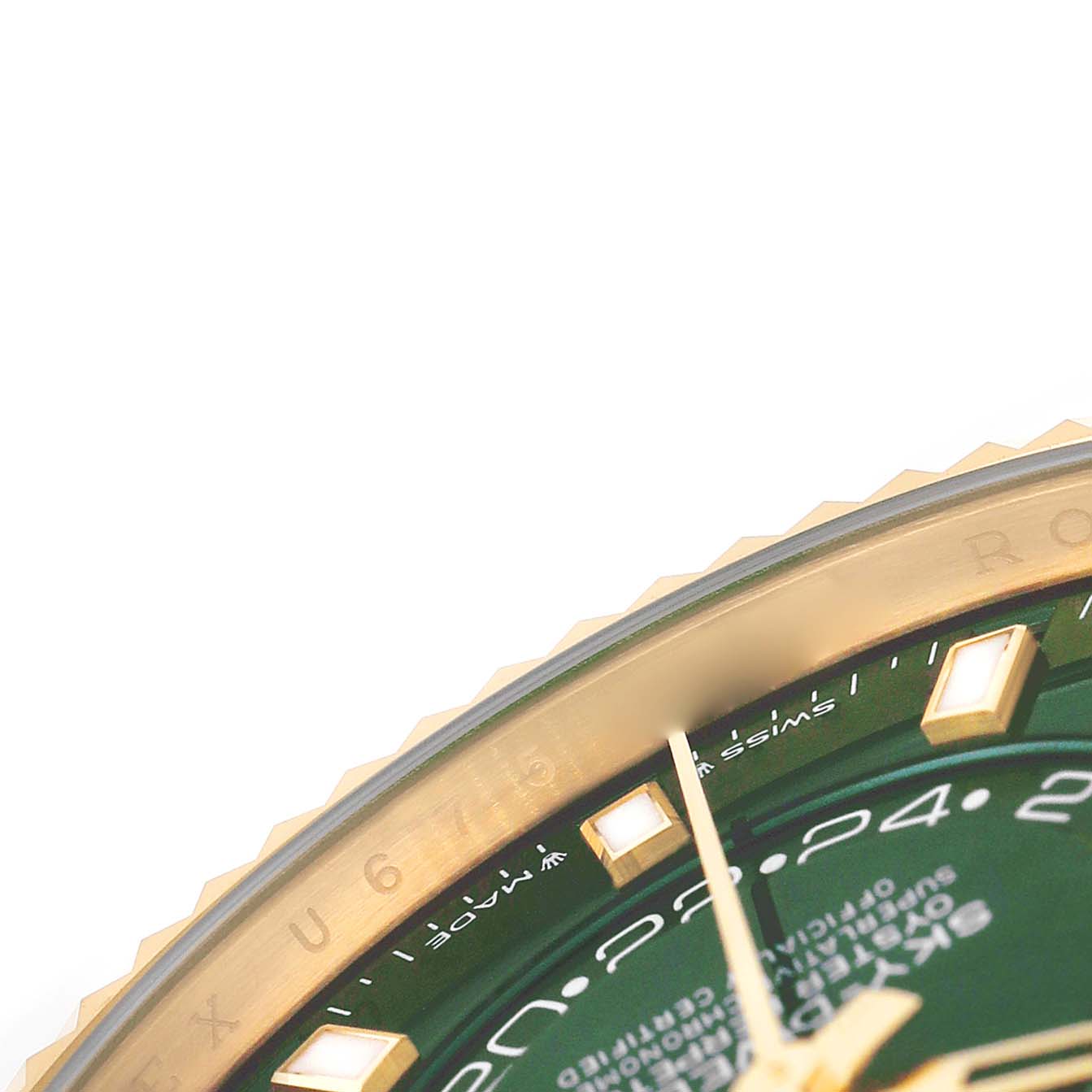 The image shows a close-up of the bezel and green dial of a Rolex Sky-Dweller 336938 Men's Yellow Gold Green Dial, highlighting part of the hour markers and text.