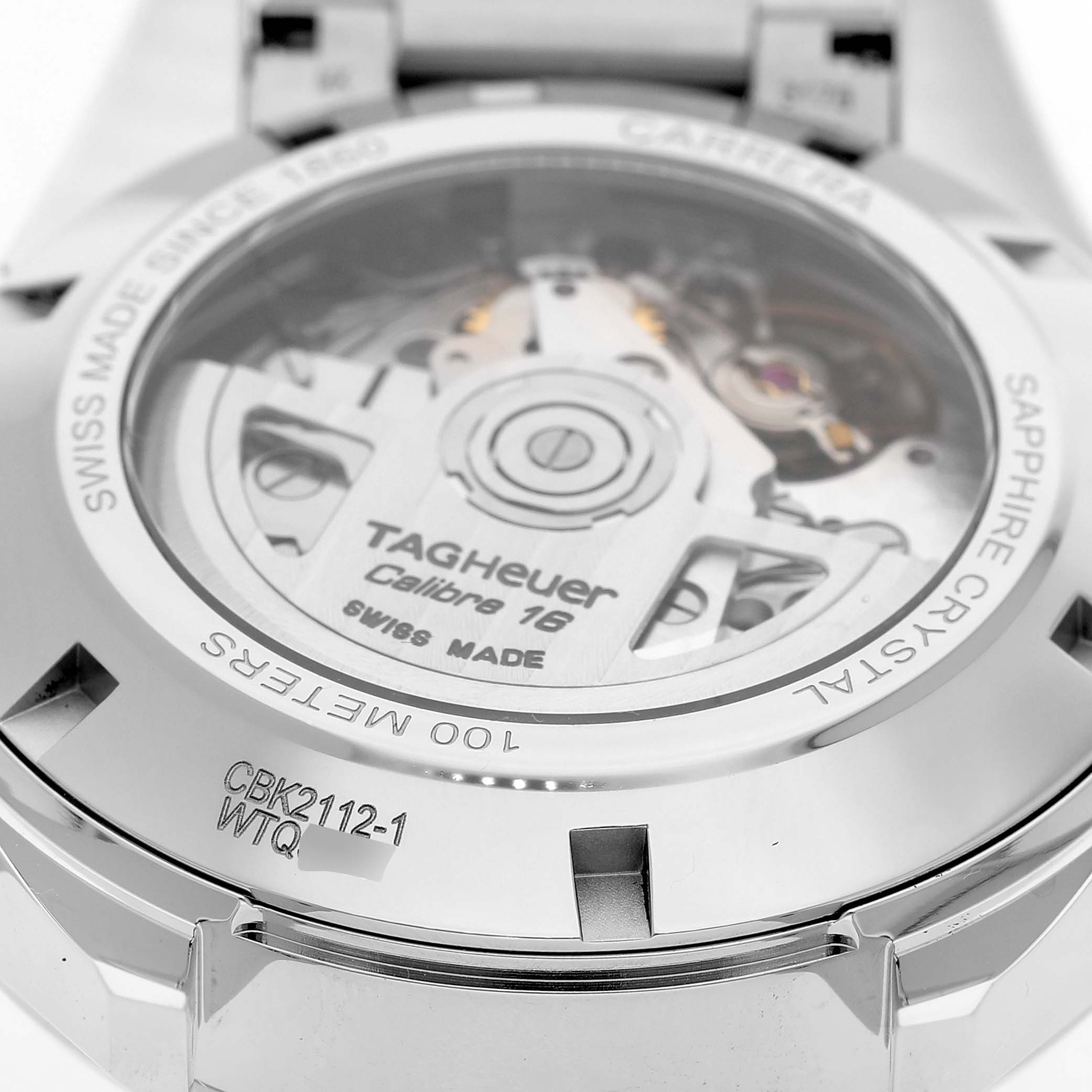 The image shows the case back of a Tag Heuer Carrera CBK2112 Men's Stainless Steel Blue Dial watch, highlighting the movement and metal casing.