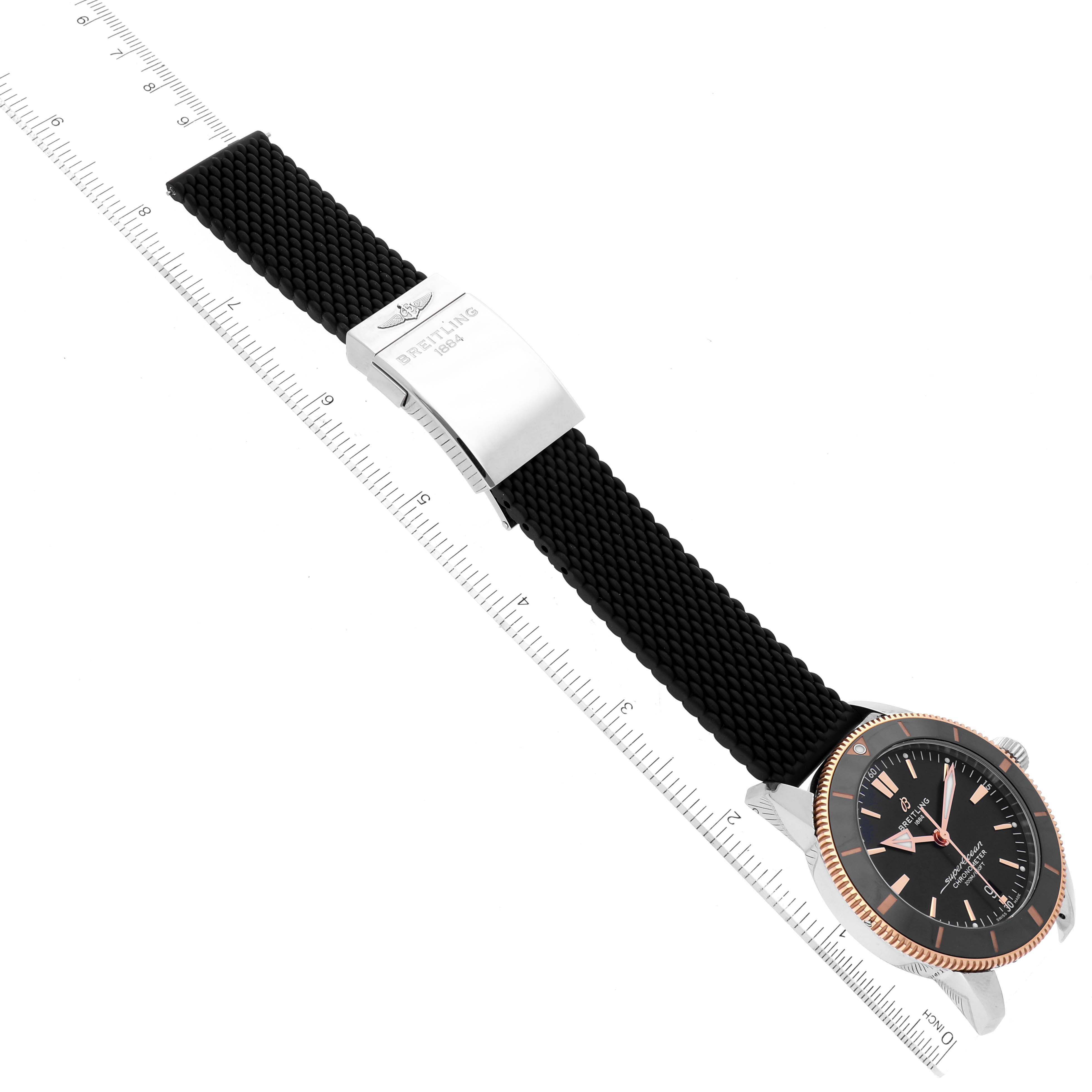 The Breitling Superocean UB2030121B1A1 Men's Steel and Gold (two tone) Black Dial UB2030121B1A1 Men's Steel and Gold (two tone) Black Dial watch is shown from a top-down angle, featuring its bezel, dial, crown, and strap with a measuring scale.