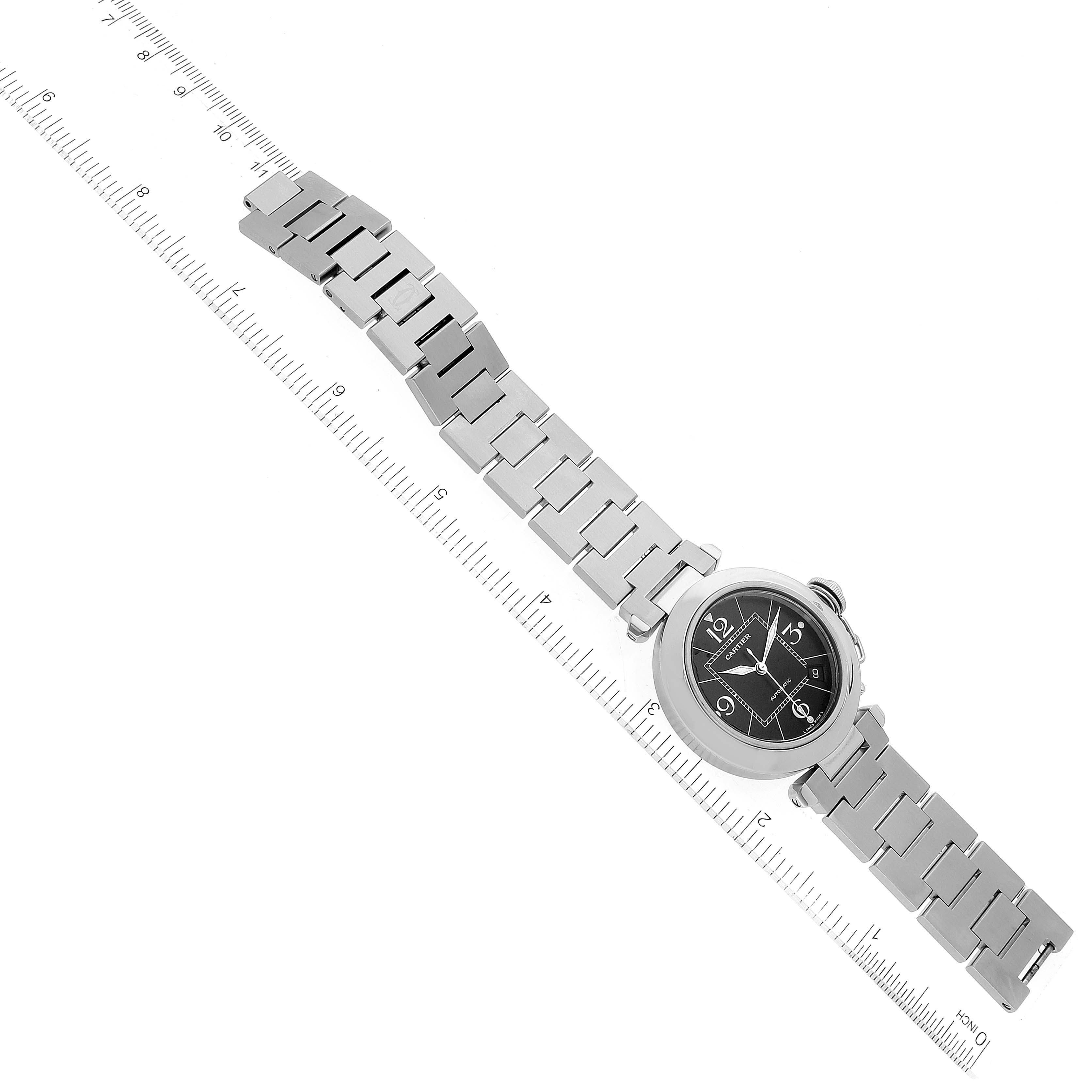 This image shows a top view of the Cartier Pasha W31076M7 Women's Stainless Steel Black Dial W31076M7 Women's Stainless Steel Black Dial watch, featuring its black dial and silver bracelet, aligned with a ruler.