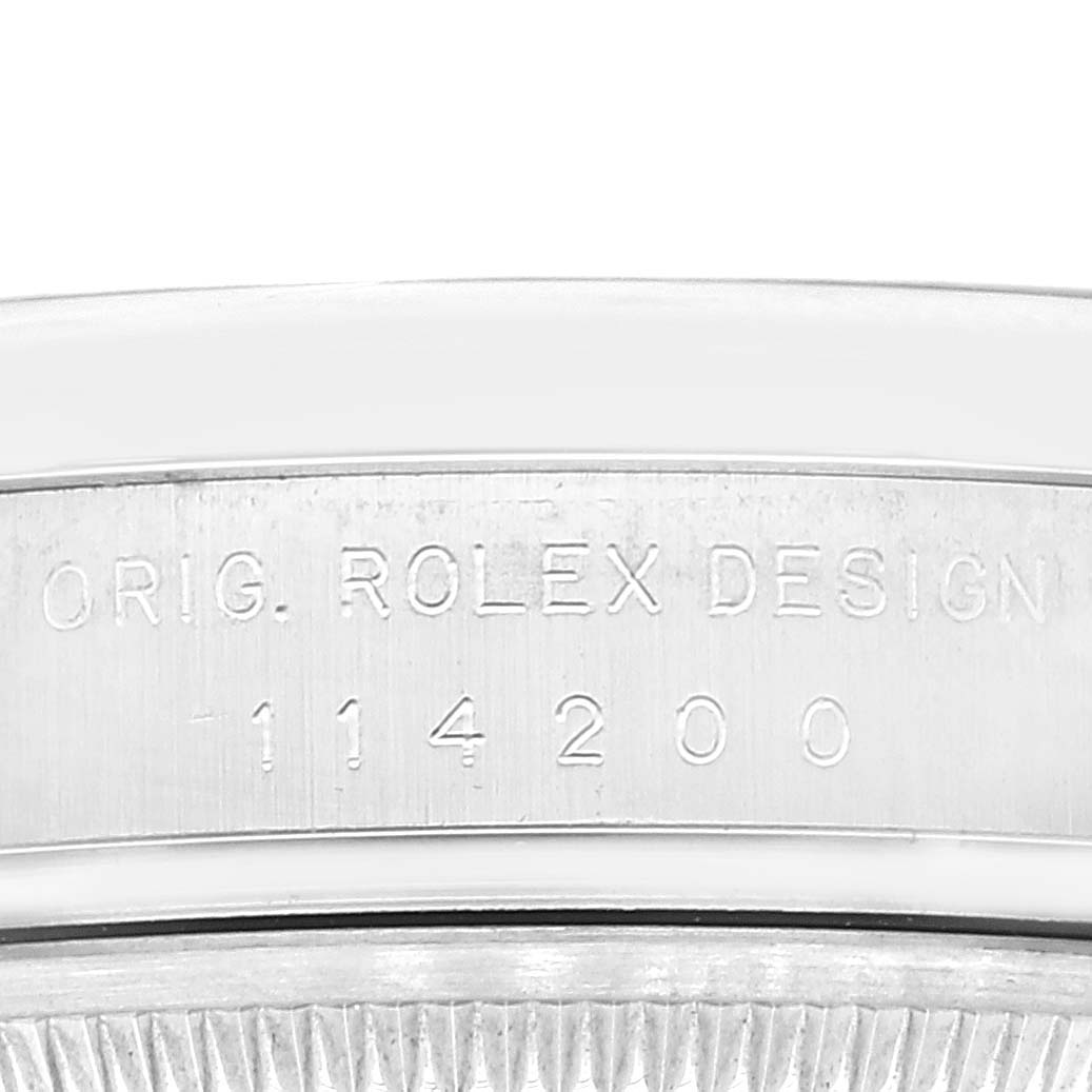The image shows a close-up of the side of a Rolex Air-King 114200 Men's Stainless Steel Pink Dial 114200 Men's Stainless Steel Pink Dial watch, highlighting the engraved model number 114200 and the text "ORIG. ROLEX DESIGN."