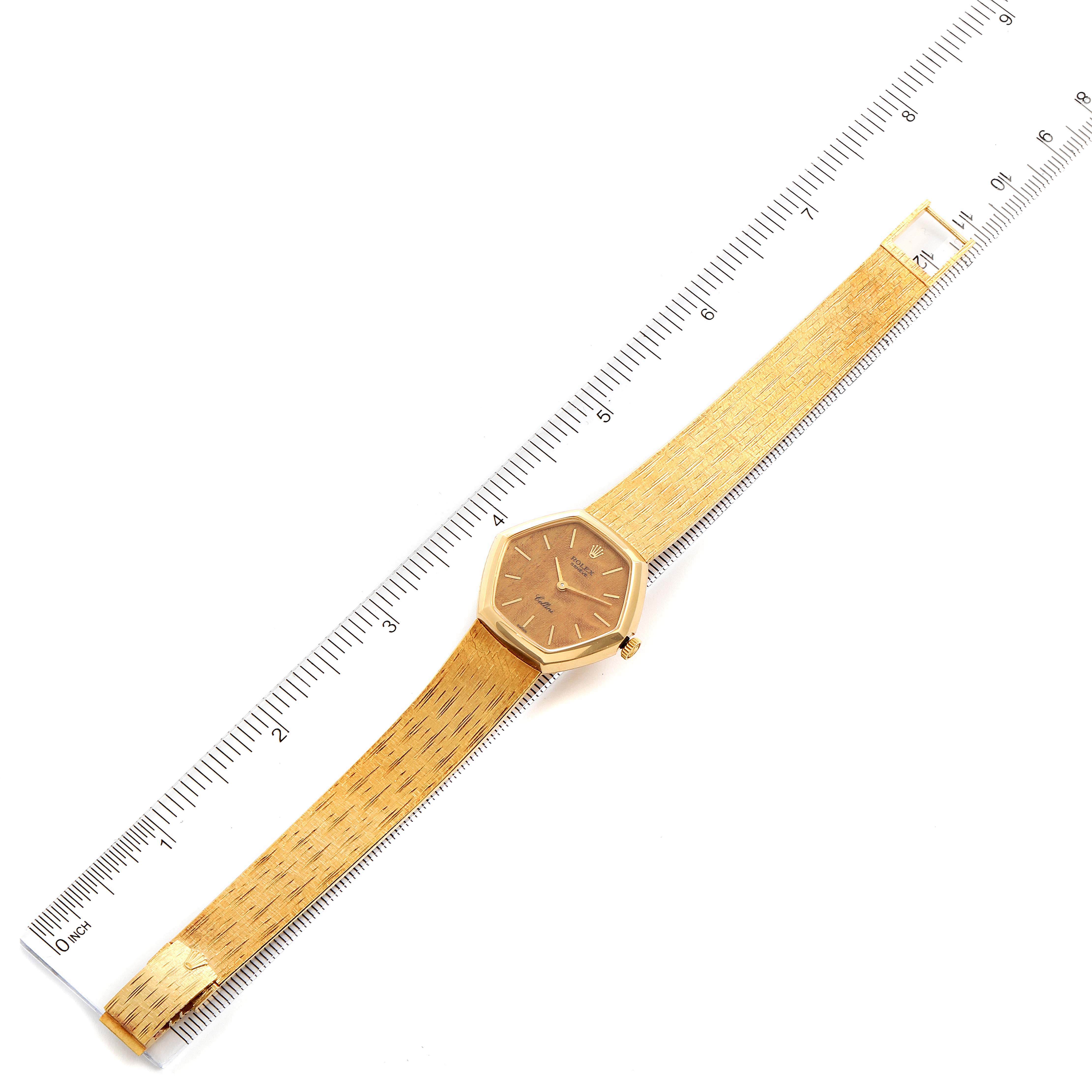 The Rolex Cellini 4303 Women's Yellow Gold Brown Dial 4303 Women's Yellow Gold Brown Dial watch is shown from a top-down angle, displaying the entire watch and its golden strap along with a measuring ruler.