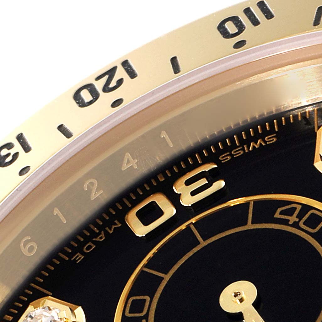 This close-up image shows the bezel and part of the black dial of a Rolex Daytona 116528 Men's Yellow Gold Black Dial 116528 Men's Yellow Gold Black Dial watch.