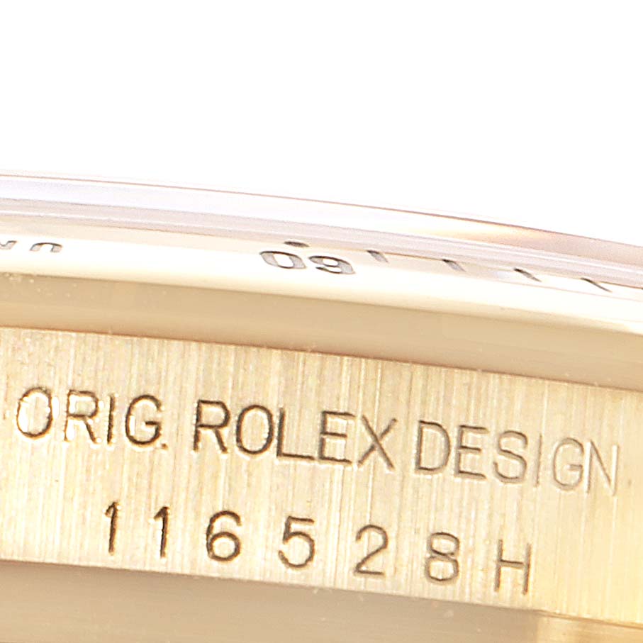 The image shows a close-up of the case side of the Rolex Daytona 116528 Men's Yellow Gold Black Dial 116528 Men's Yellow Gold Black Dial, specifically the engraved serial number and part of the bezel.