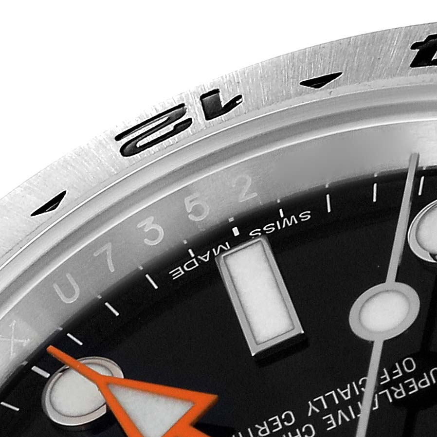 A close-up of the Rolex Explorer 216570 Men
s Stainless Steel Black Dial 216570 Men
s Stainless Steel Black Dial watch showing part of the bezel, hour markers, and the orange hour hand.