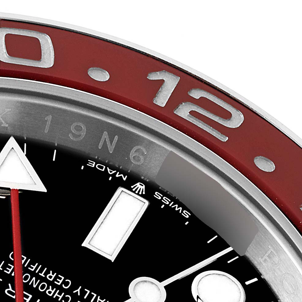 This close-up of a Rolex GMT-Master 126710 Men's Stainless Steel Black Dial 126710 Men's Stainless Steel Black Dial watch shows the bezel with the 12 o'clock marker, part of the dial, and a portion of the hands.