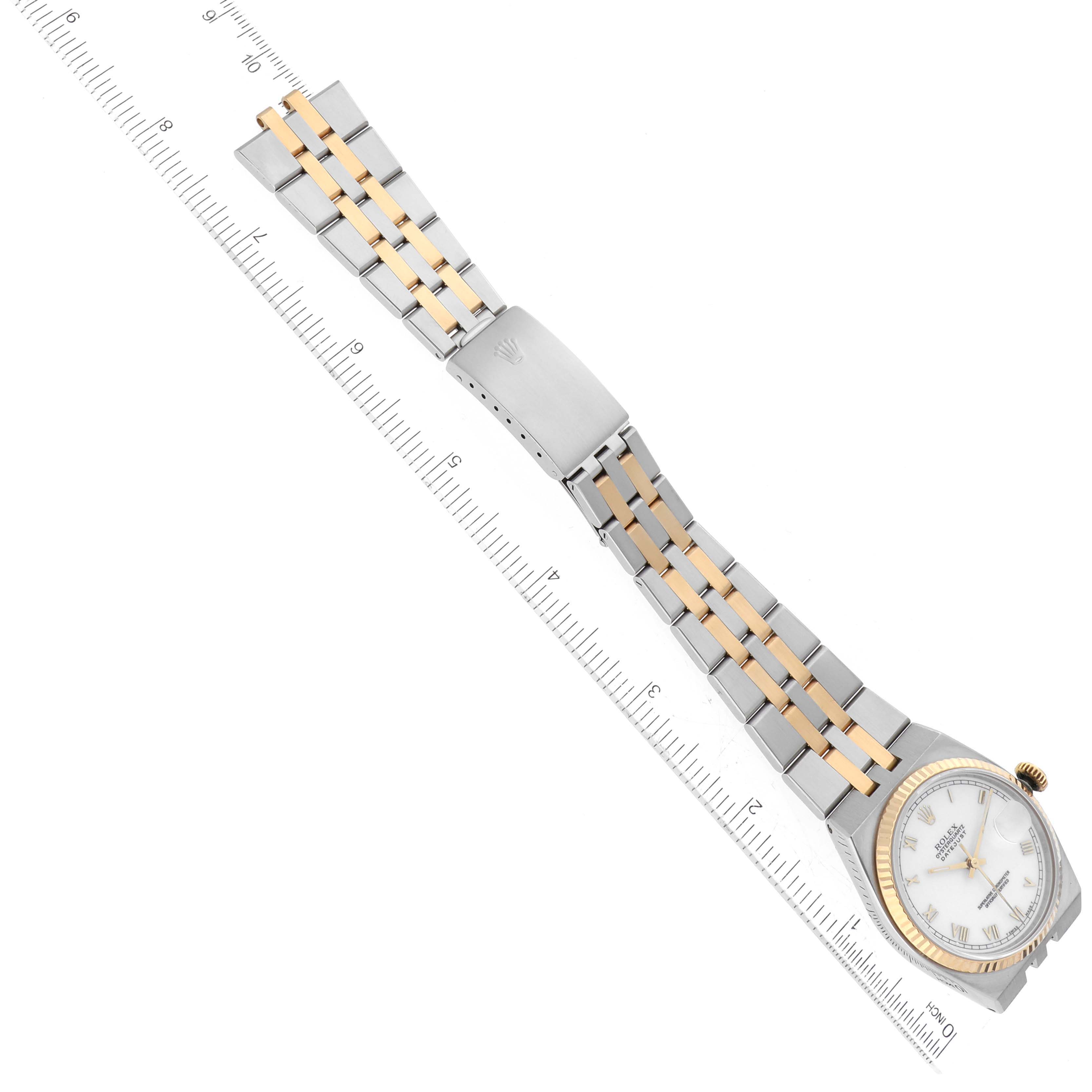 The image shows a top-down view of a Rolex Oysterquartz 17013 Men
s Steel and Gold (two tone) White Dial 17013 Men
s Steel and Gold (two tone) White Dial watch, highlighting its face, bezel, and band next to a ruler for scale.