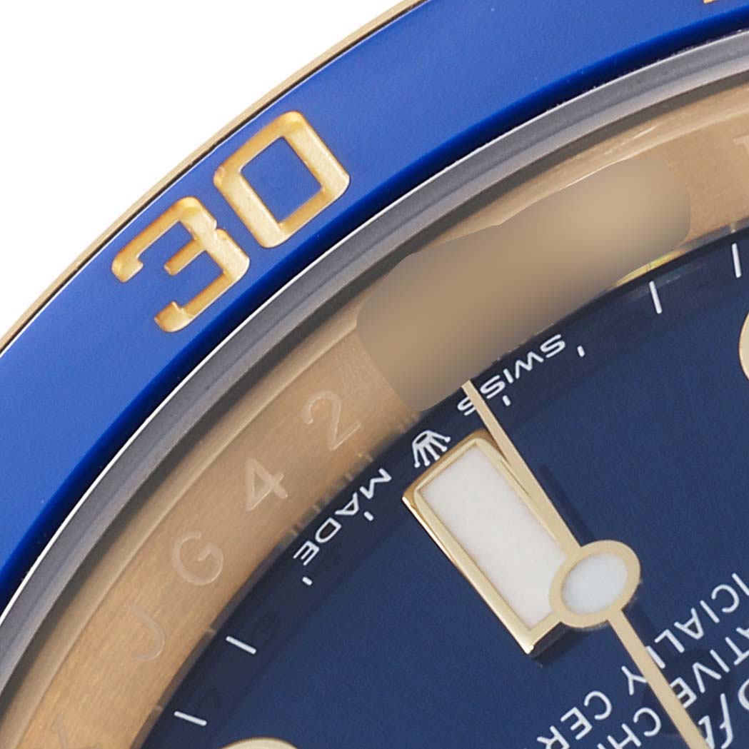 This close-up angle of a Rolex Submariner 126618LB Men's Yellow Gold Blue Dial 126618LB Men's Yellow Gold Blue Dial watch shows part of the blue bezel with gold numbers and a section of the watch face.