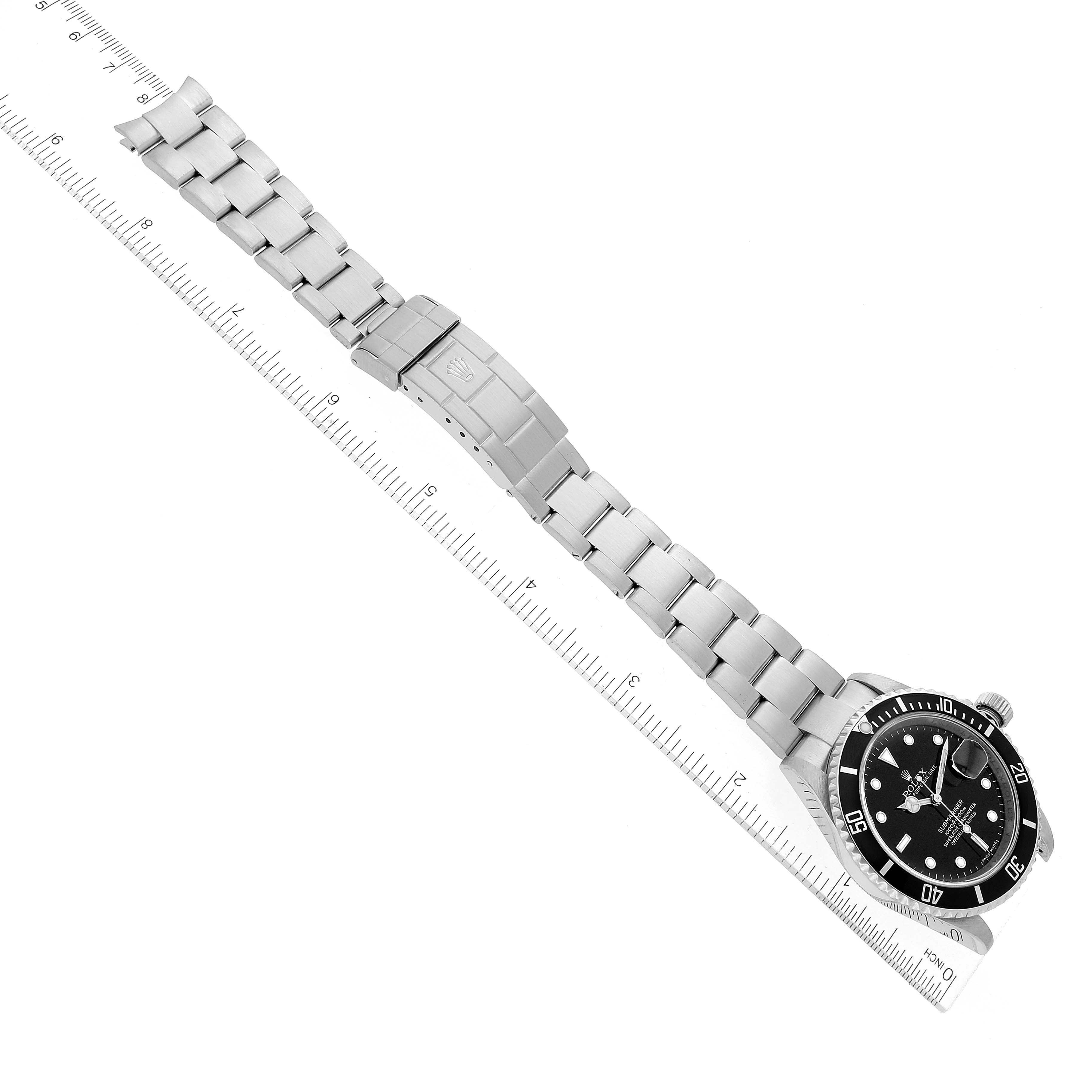 This image shows a top-down view of a Rolex Submariner 16610 Men
s Stainless Steel Black Dial 16610 Men
s Stainless Steel Black Dial watch, including its stainless steel band and clasp, along with a measuring ruler.
