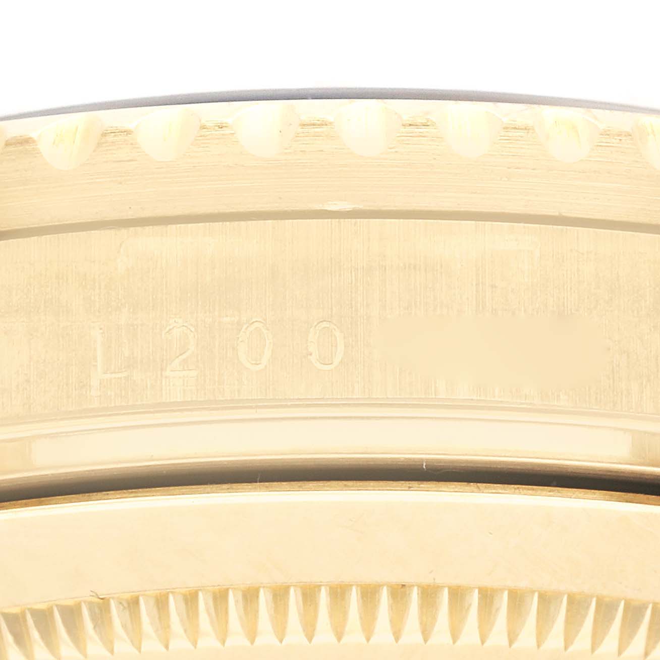 This close-up shot of a Rolex Submariner 16618 Men's Yellow Gold Black Dial 16618 Men's Yellow Gold Black Dial shows a portion of the bezel, case side, and engraved model details.