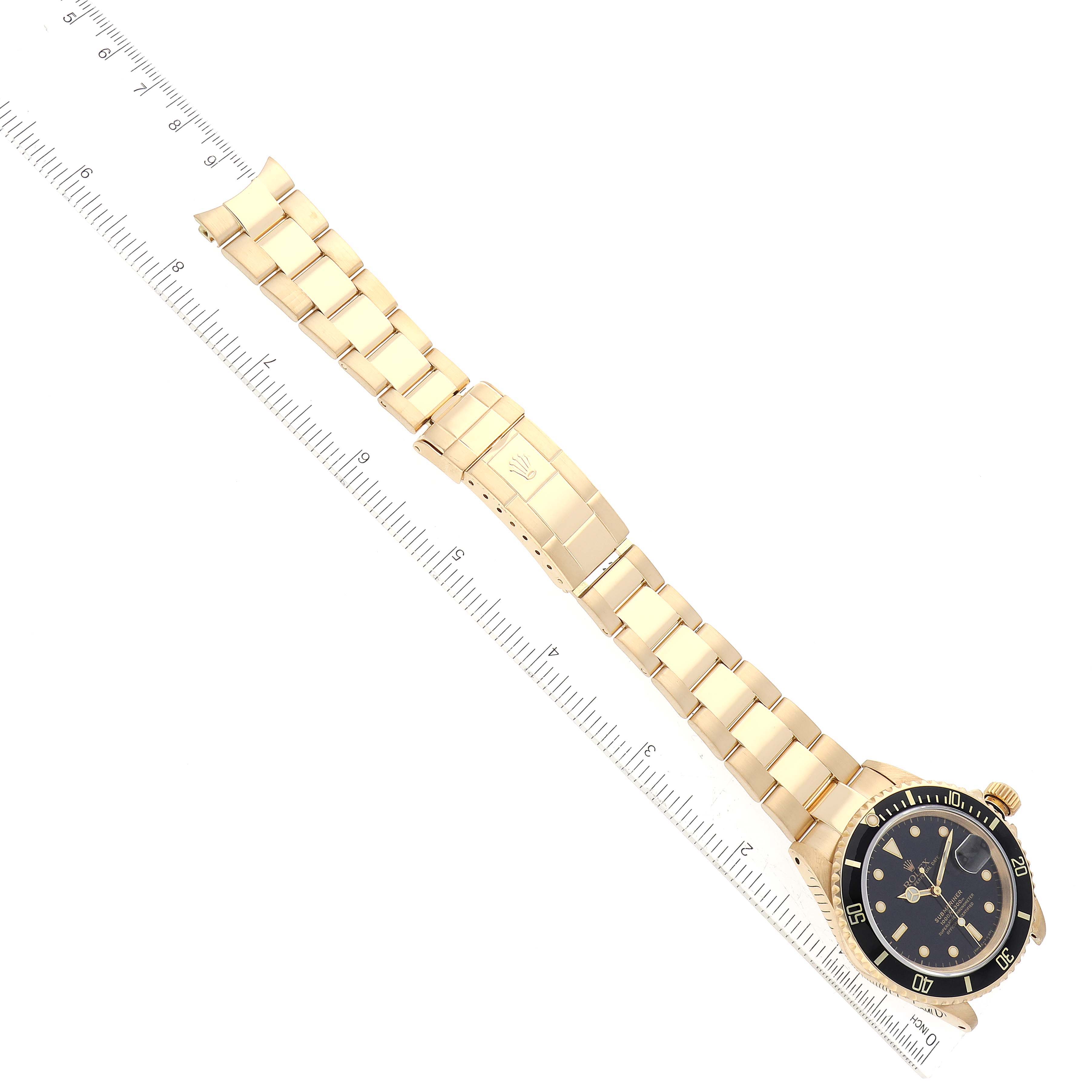The image shows a Rolex Submariner 16618 Men's Yellow Gold Black Dial 16618 Men's Yellow Gold Black Dial watch photographed diagonally, displaying the face, bezel, crown, and bracelet with a ruler for scale.