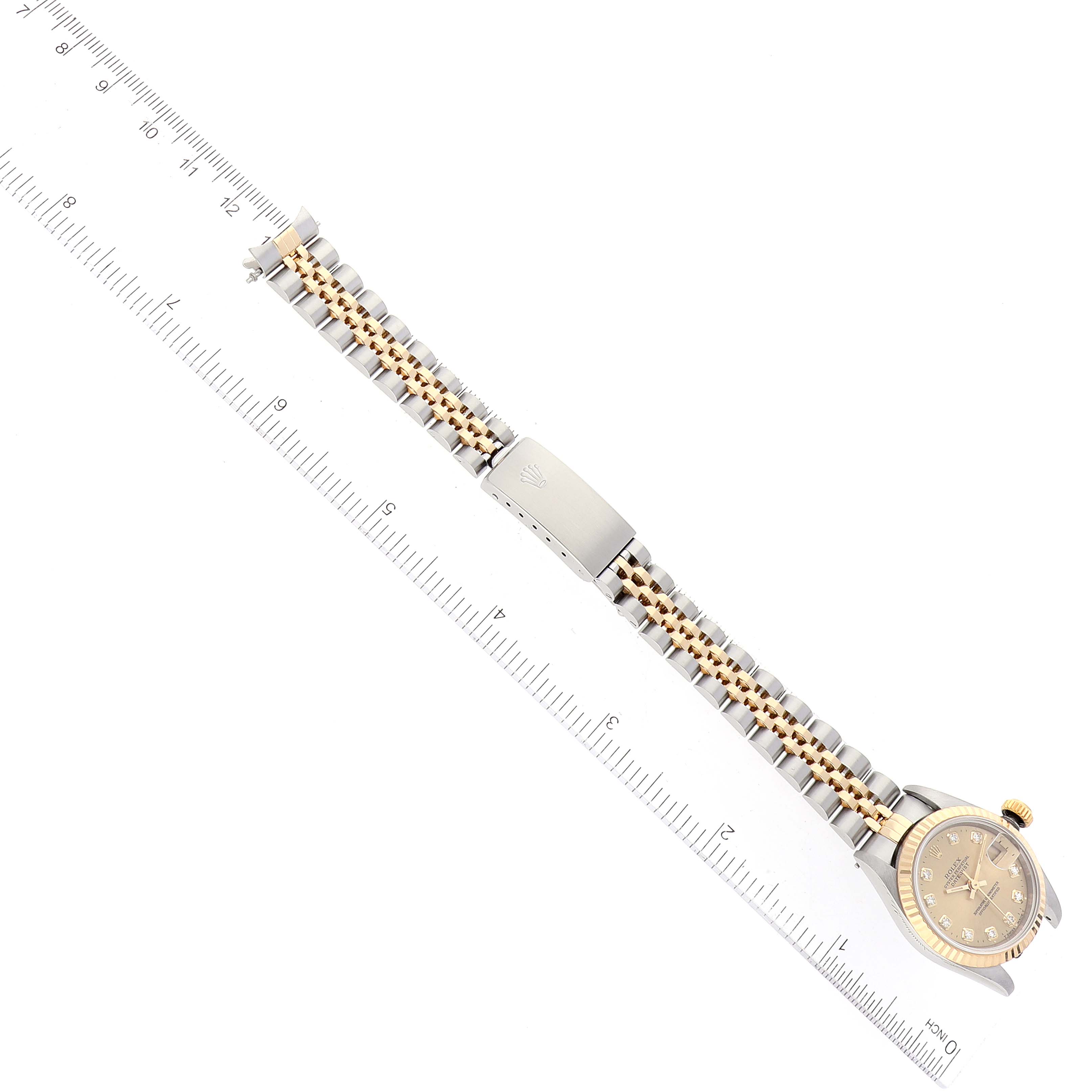 The image shows a top-down view of a Rolex Datejust 69173 Women's Steel and Gold (two tone) Champagne Dial 69173 Women's Steel and Gold (two tone) Champagne Dial watch with its full bracelet and clasp, along with a measuring ruler beside it.