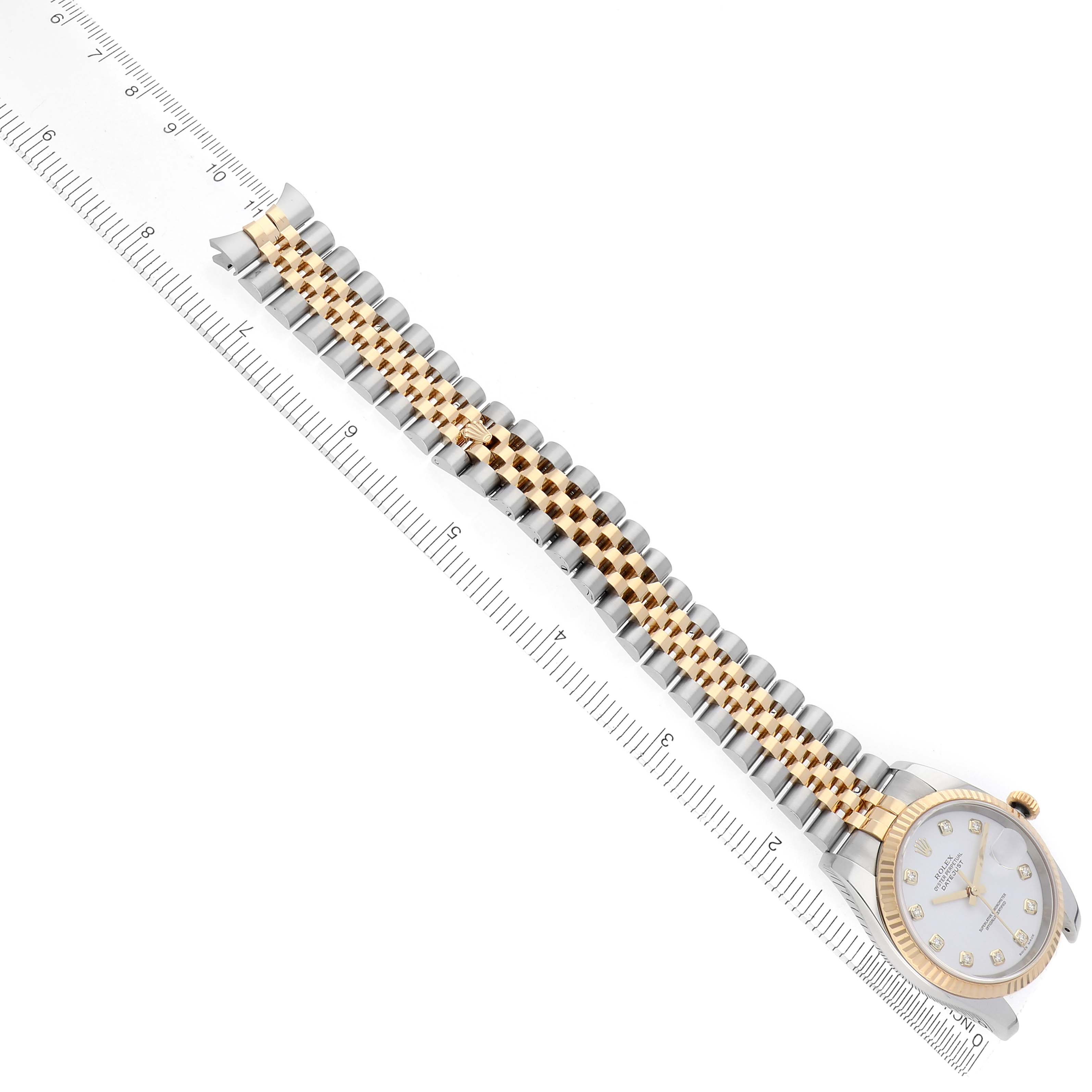 The image shows a Rolex Datejust 116233 Men
s Steel and Gold (two tone) White Dial 116233 Men
s Steel and Gold (two tone) White Dial watch at an angle, highlighting the gold and silver bracelet against a ruler.