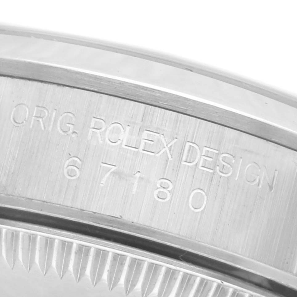 The image shows a close-up of the case side of a Rolex Oyster Perpetual 67180 Women's Stainless Steel Pink Dial 67180 Women's Stainless Steel Pink Dial, featuring engravings of "ORIG. ROLEX DESIGN" and a model number.