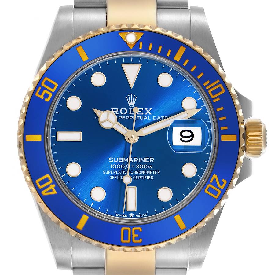 The watch is a Rolex Submariner, shown from the front featuring the blue and gold bezel, dial, and bracelet.