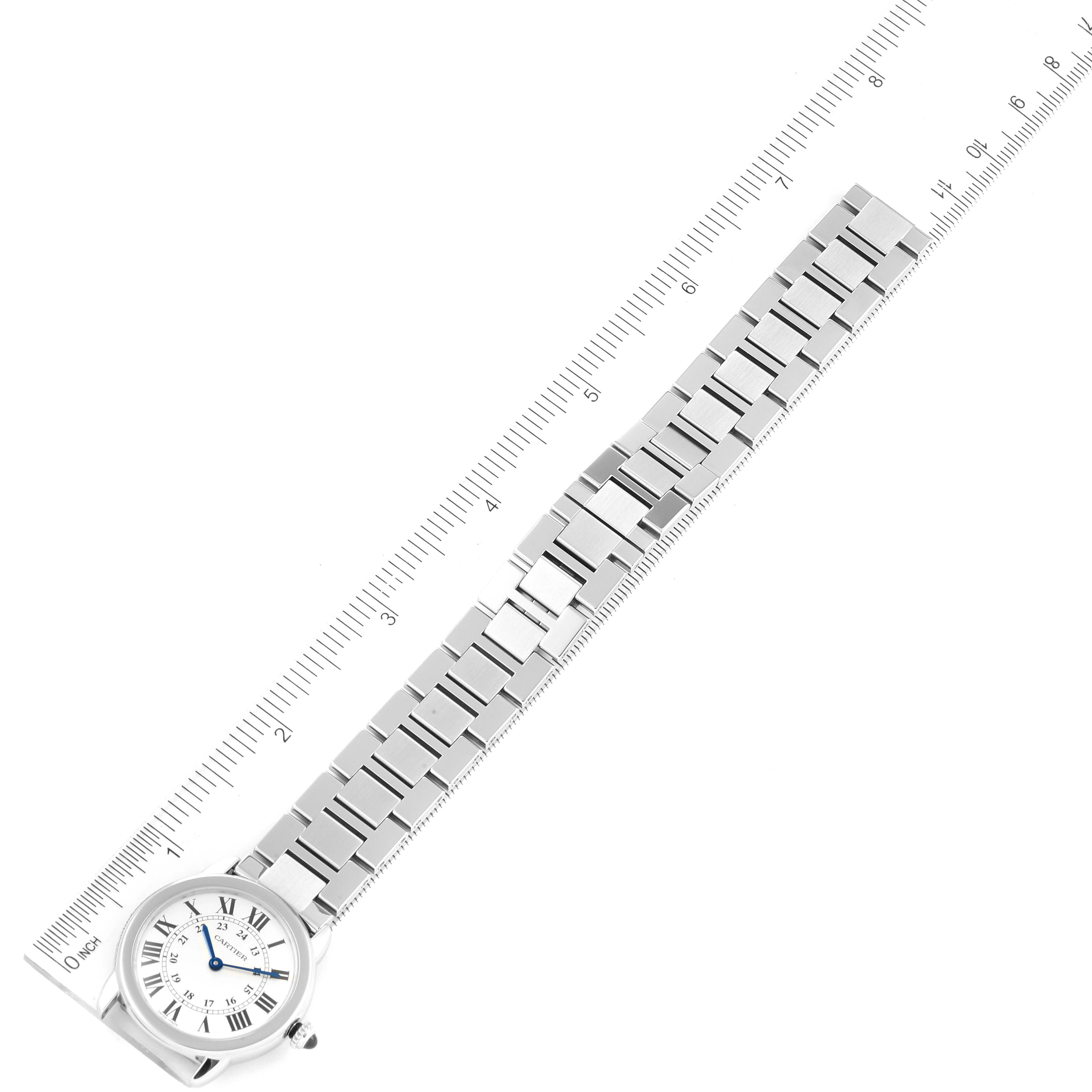 The image shows a top-down view of the Cartier Ronde W6701004 Women's Stainless Steel Silver Dial W6701004 Women's Stainless Steel Silver Dial model watch, highlighting its face and metal strap alongside a ruler.