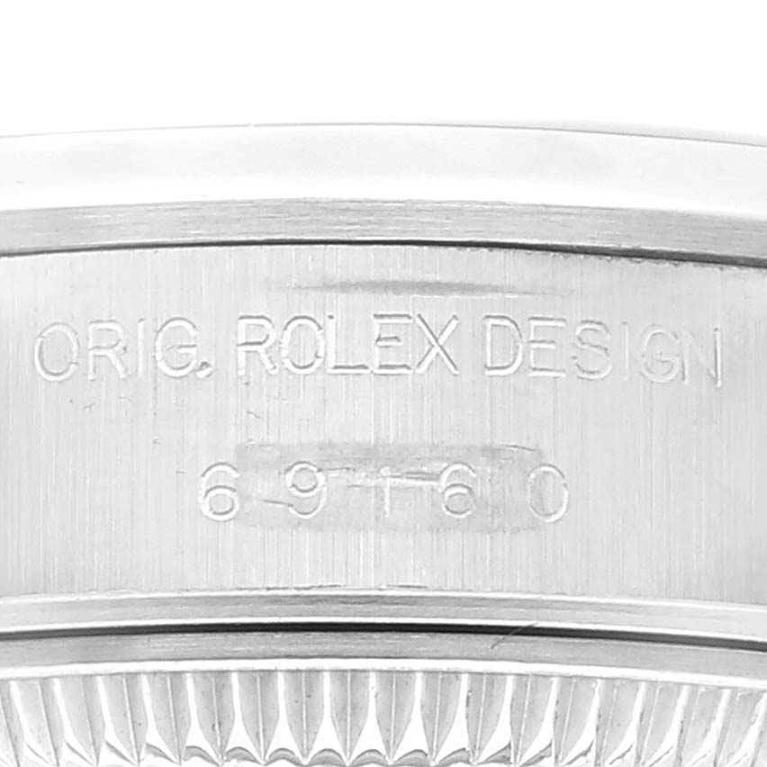 The image shows a macro view of the side of a Rolex Date 69160 Women
s Stainless Steel Blue Dial 69160 Women
s Stainless Steel Blue Dial model, specifically displaying the engraved serial number and "Orig. Rolex Design".