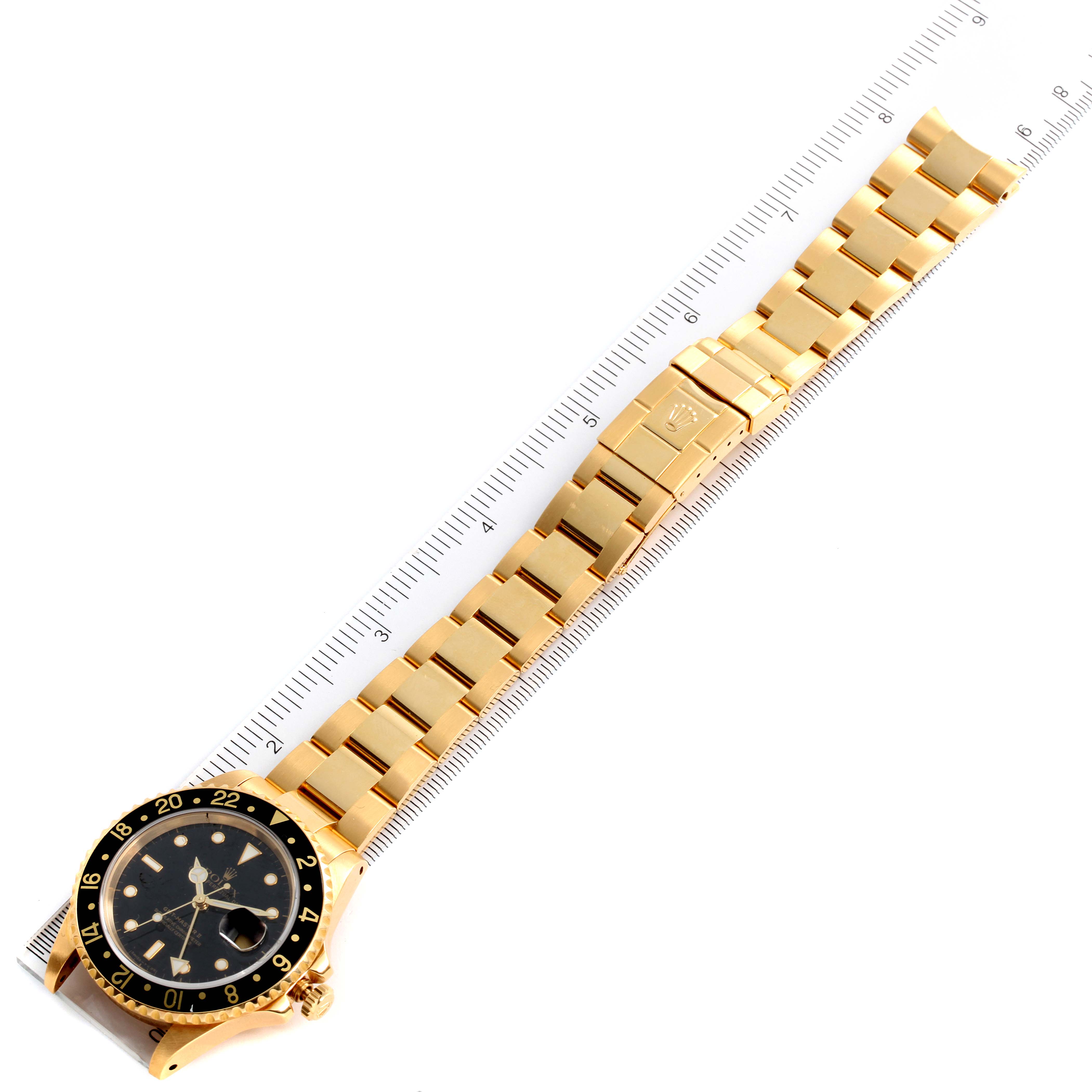 This image shows a top view of a Rolex GMT-Master 16718 Men's Yellow Gold Black Dial 16718 Men's Yellow Gold Black Dial watch, highlighting its gold bracelet and black bezel with a ruler for scale.