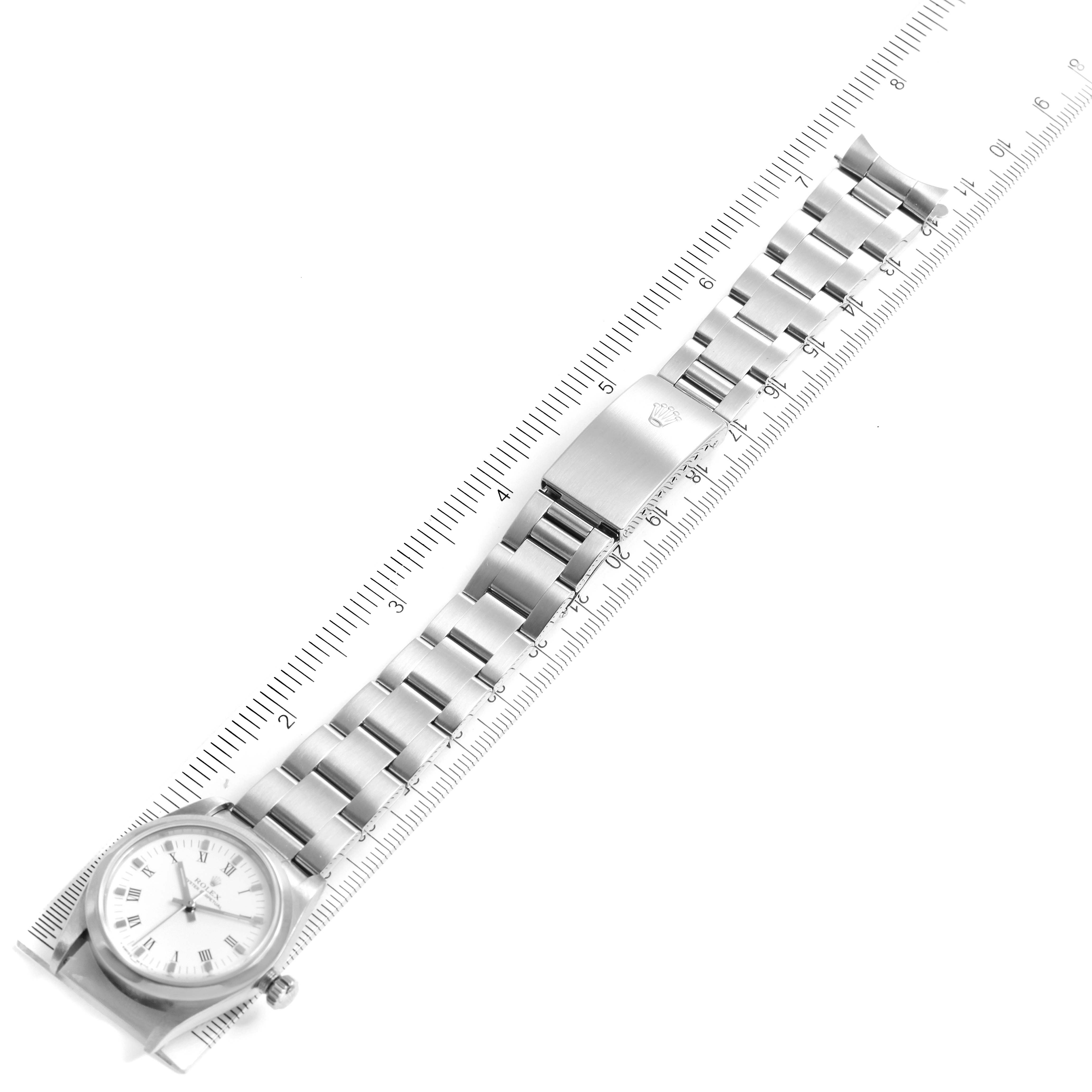 The image shows a top-down view of a Rolex Mid-Size 77080 Women
s Stainless Steel White Dial 77080 Women
s Stainless Steel White Dial watch, including its face, bracelet, and clasp, aligned with a ruler.