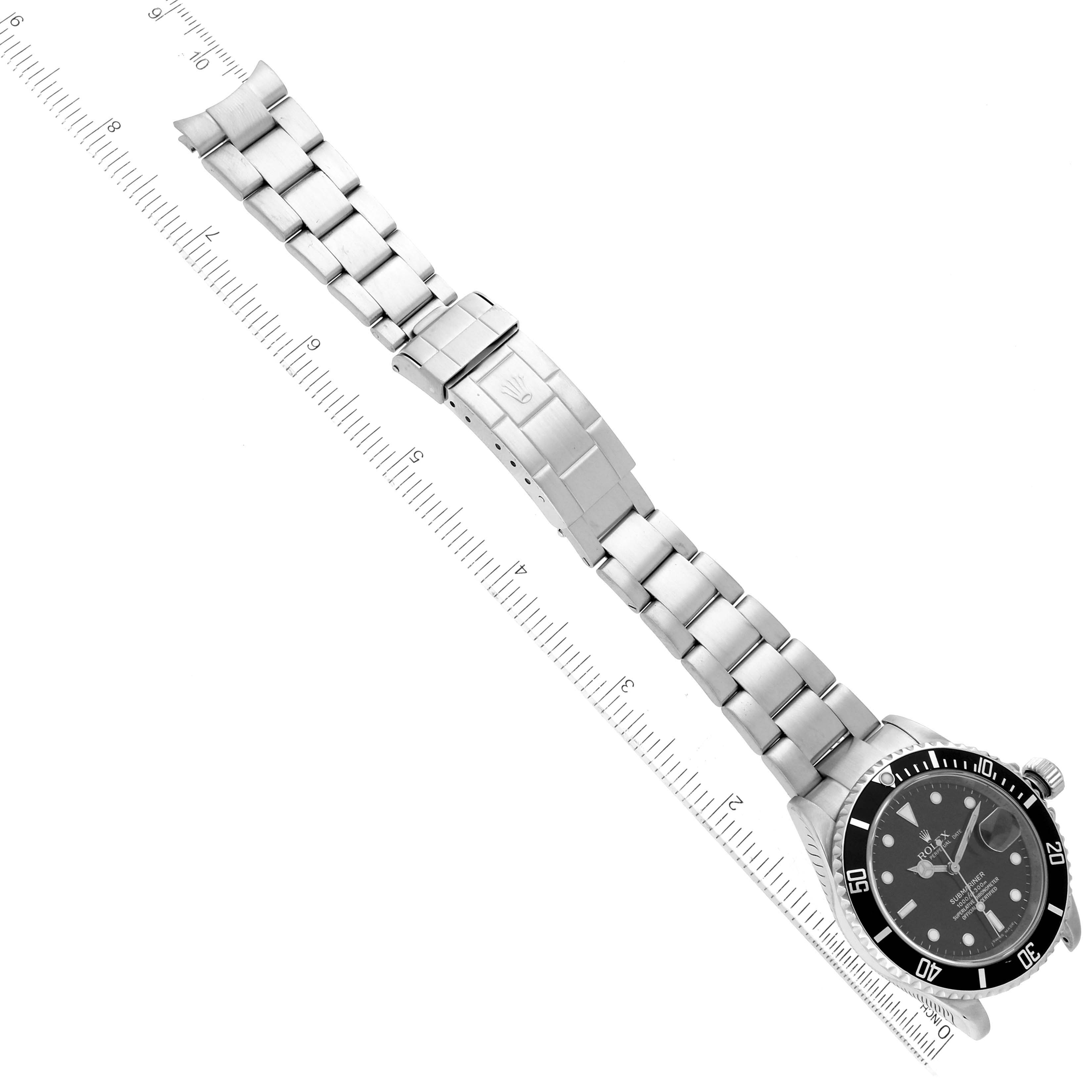 The image shows a Rolex Submariner 16610 Men
s Stainless Steel Black Dial 16610 Men
s Stainless Steel Black Dial watch laid flat next to a ruler, displaying the face, bezel, and full bracelet.