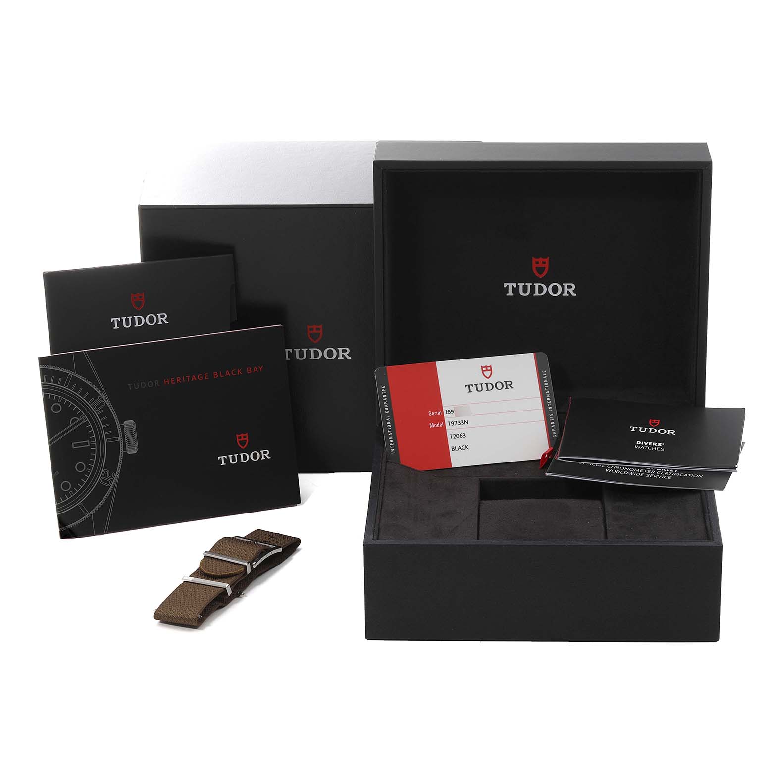 This image shows the box, warranty card, manuals, and an additional strap for the Tudor Heritage Black Bay 79733 Men's Steel and Gold (two tone) Black Dial 79733 Men's Steel and Gold (two tone) Black Dial model watch.