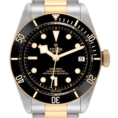 The image shows a front view of a Tudor Heritage Black Bay watch, highlighting its black dial, gold accents, and date display.