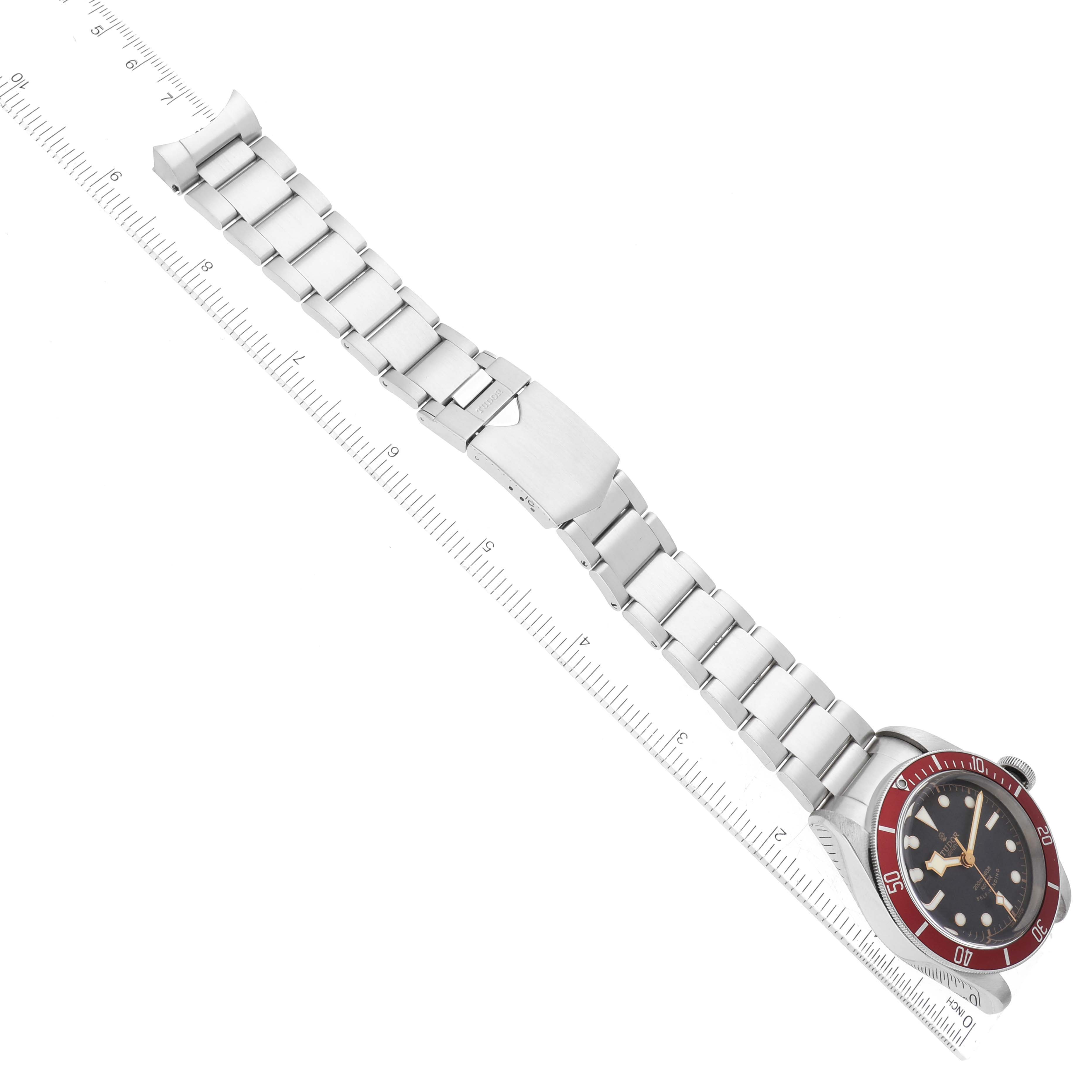 The image shows an overhead view of the Tudor Heritage Black Bay 79220R Men's Stainless Steel Black Dial 79220R Men's Stainless Steel Black Dial watch, displaying its full bracelet, clasp, and face on a ruler for scale.