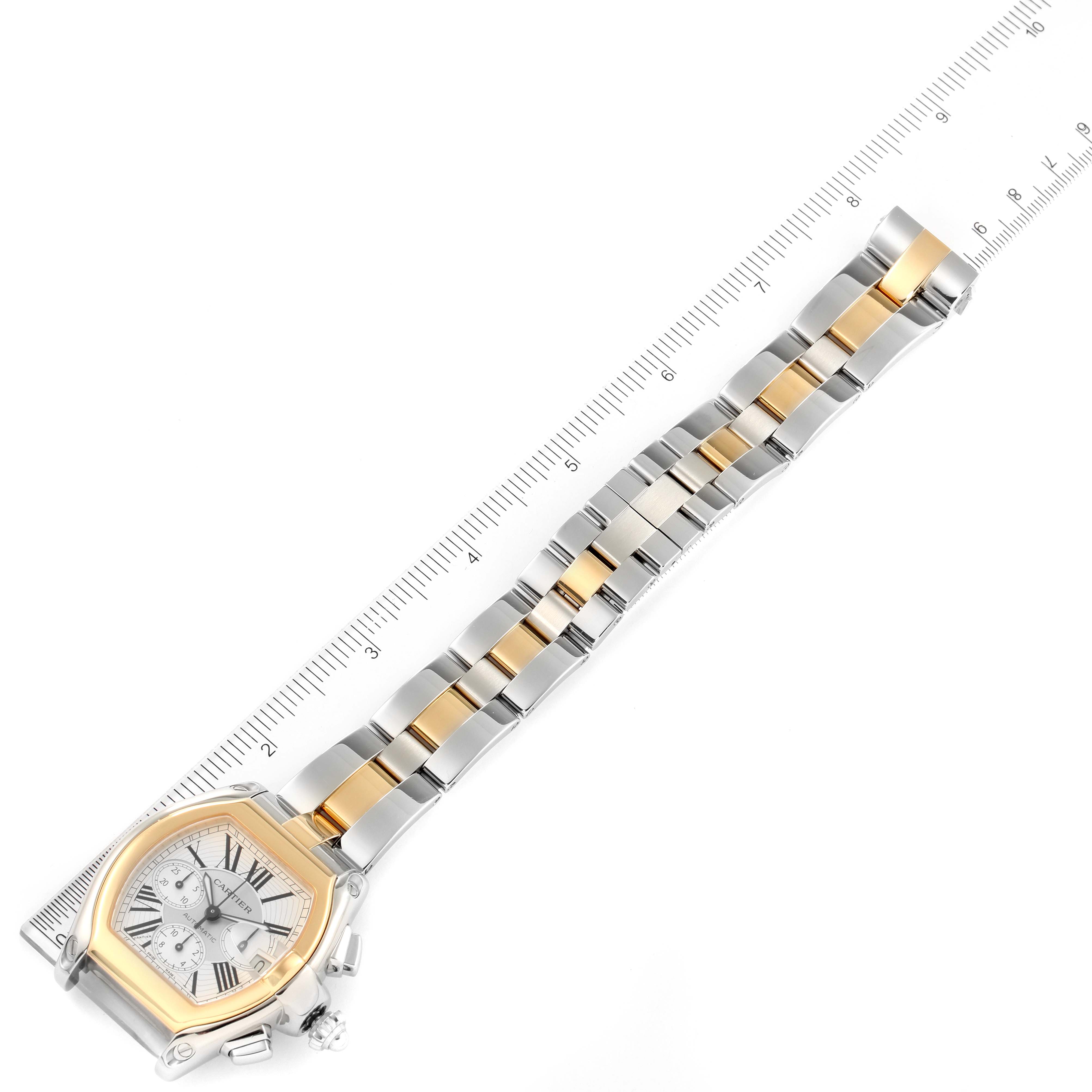 This image shows the Cartier Roadster W62027Z1 Men's Steel and Gold (two tone) Silver Dial W62027Z1 Men's Steel and Gold (two tone) Silver Dial watch laid flat next to a ruler, displaying the face, bezel, and full bracelet.