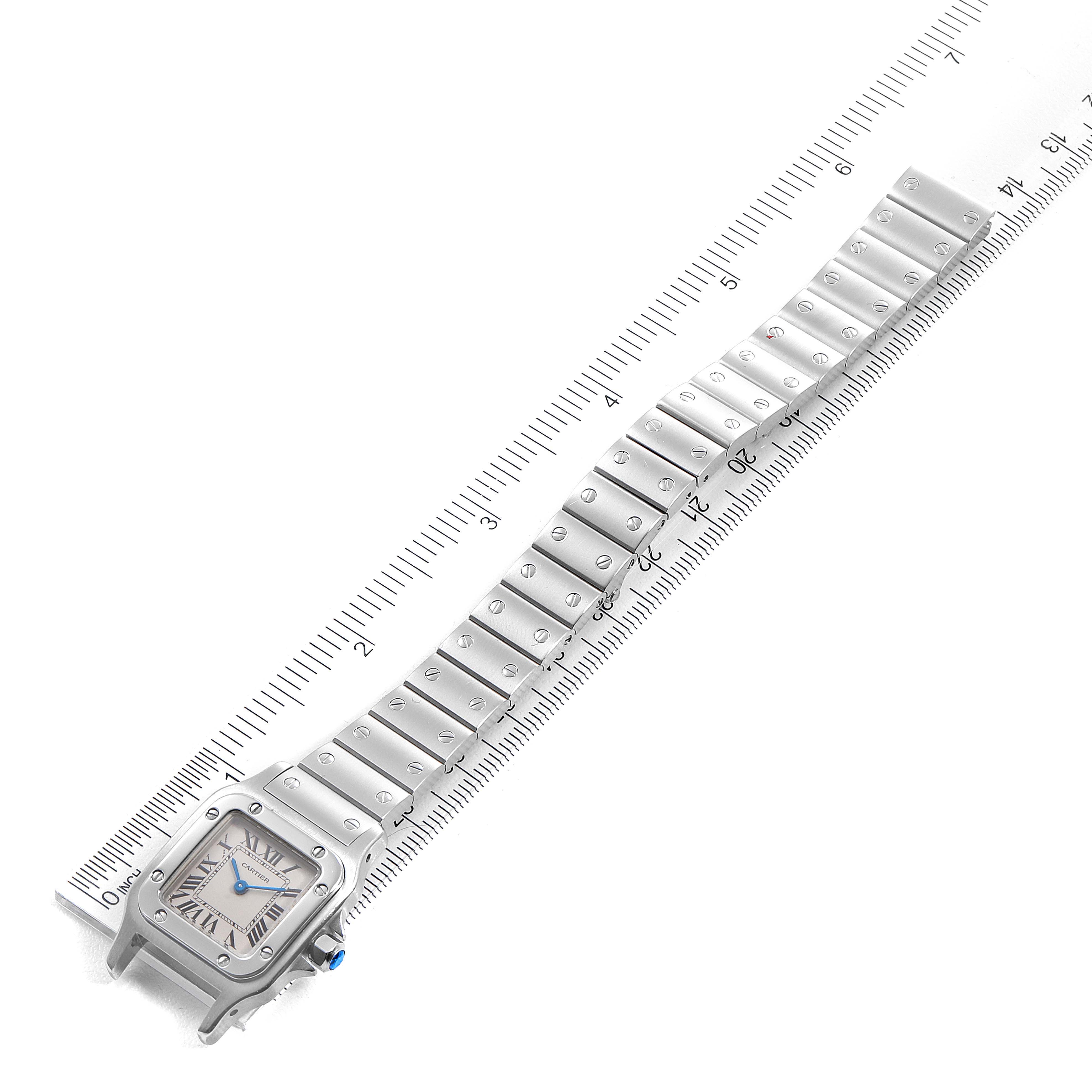 The image shows a top-down view of the Cartier Santos W20056D6 Women's Stainless Steel Silver Dial W20056D6 Women's Stainless Steel Silver Dial watch and its metal bracelet on a ruler for measurement.