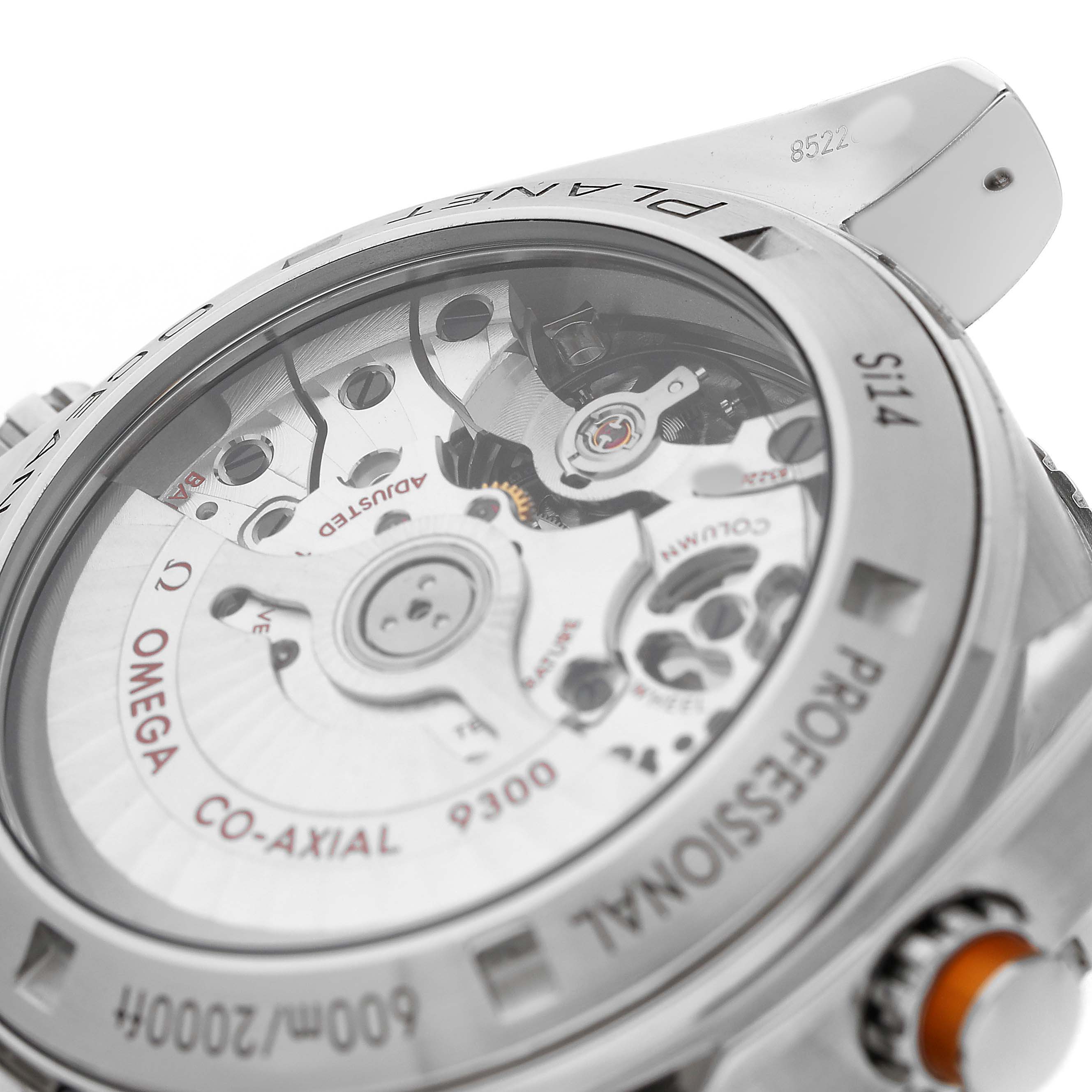 The image shows the back view of an Omega Planet Ocean 232.30.46.51.01.002 Men's Stainless Steel Black Dial watch, highlighting its Co-Axial movement and detailed engraving.