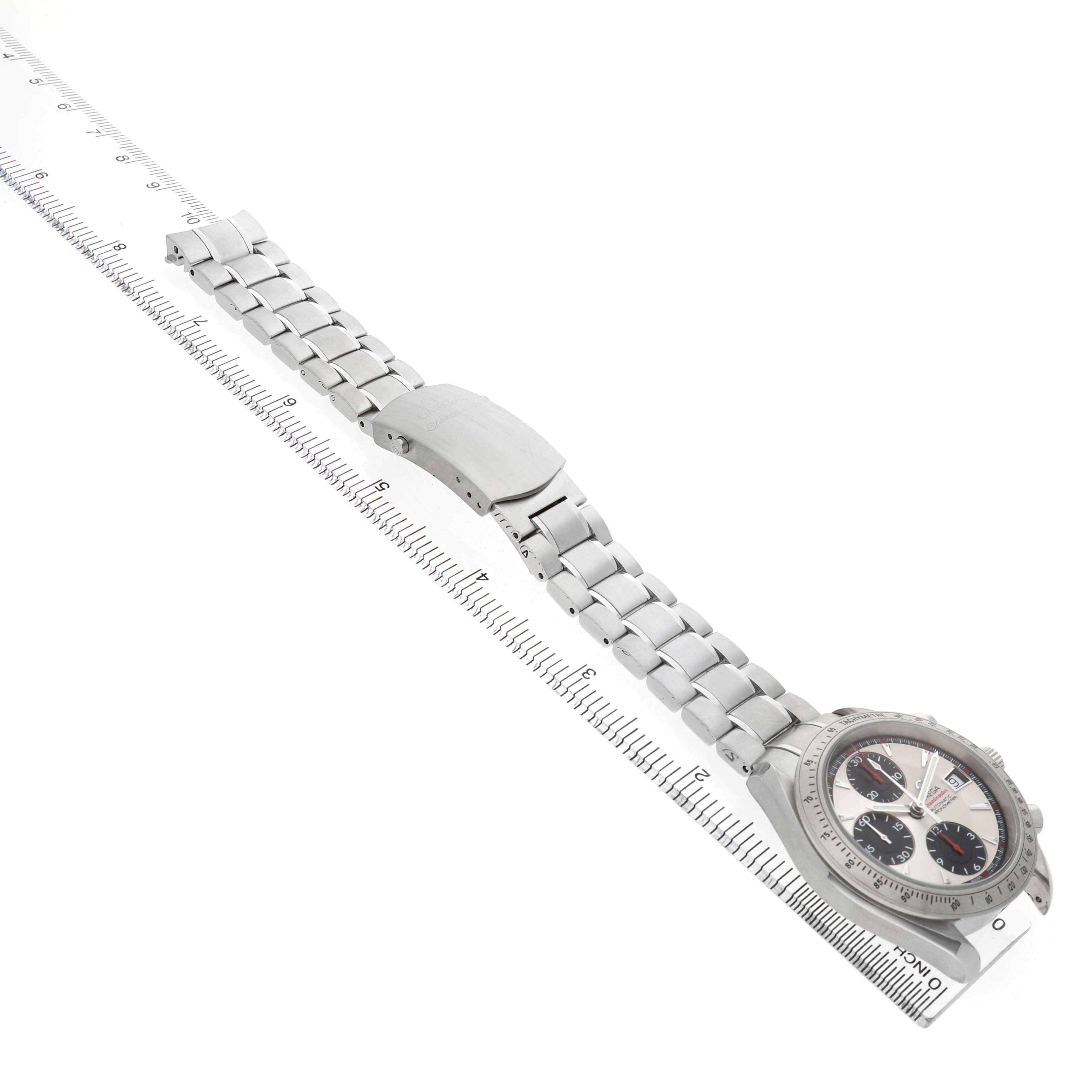 The Omega Speedmaster 3211.31.00 Men's Stainless Steel Silver Dial watch is shown from a top view, featuring the dial, bezel, bracelet, and clasp near a ruler.