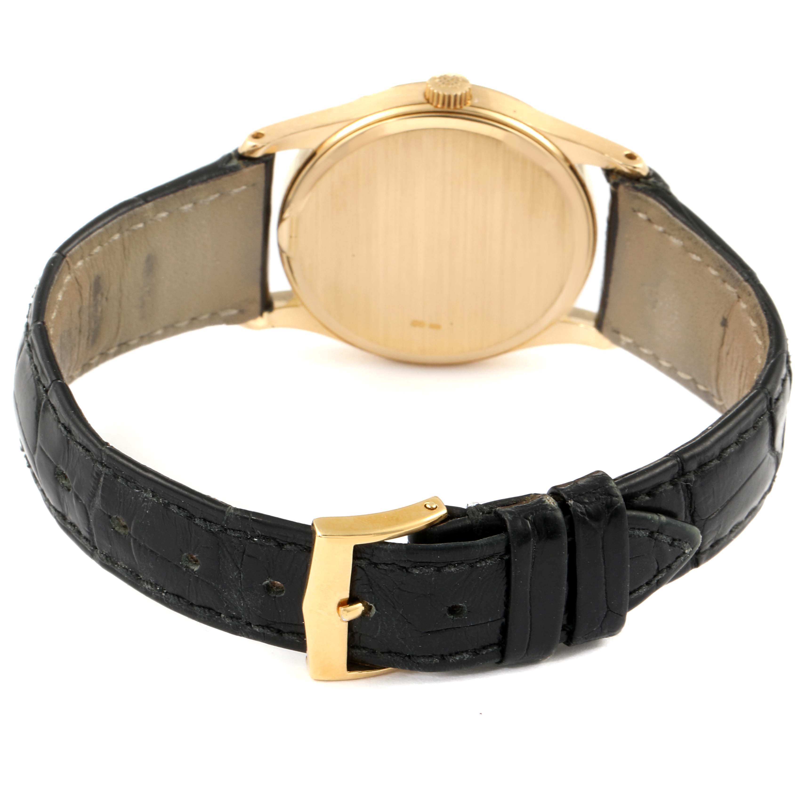 The image shows the backside of a Vintage Patek Philippe watch, highlighting its case back, black leather strap, and gold buckle.