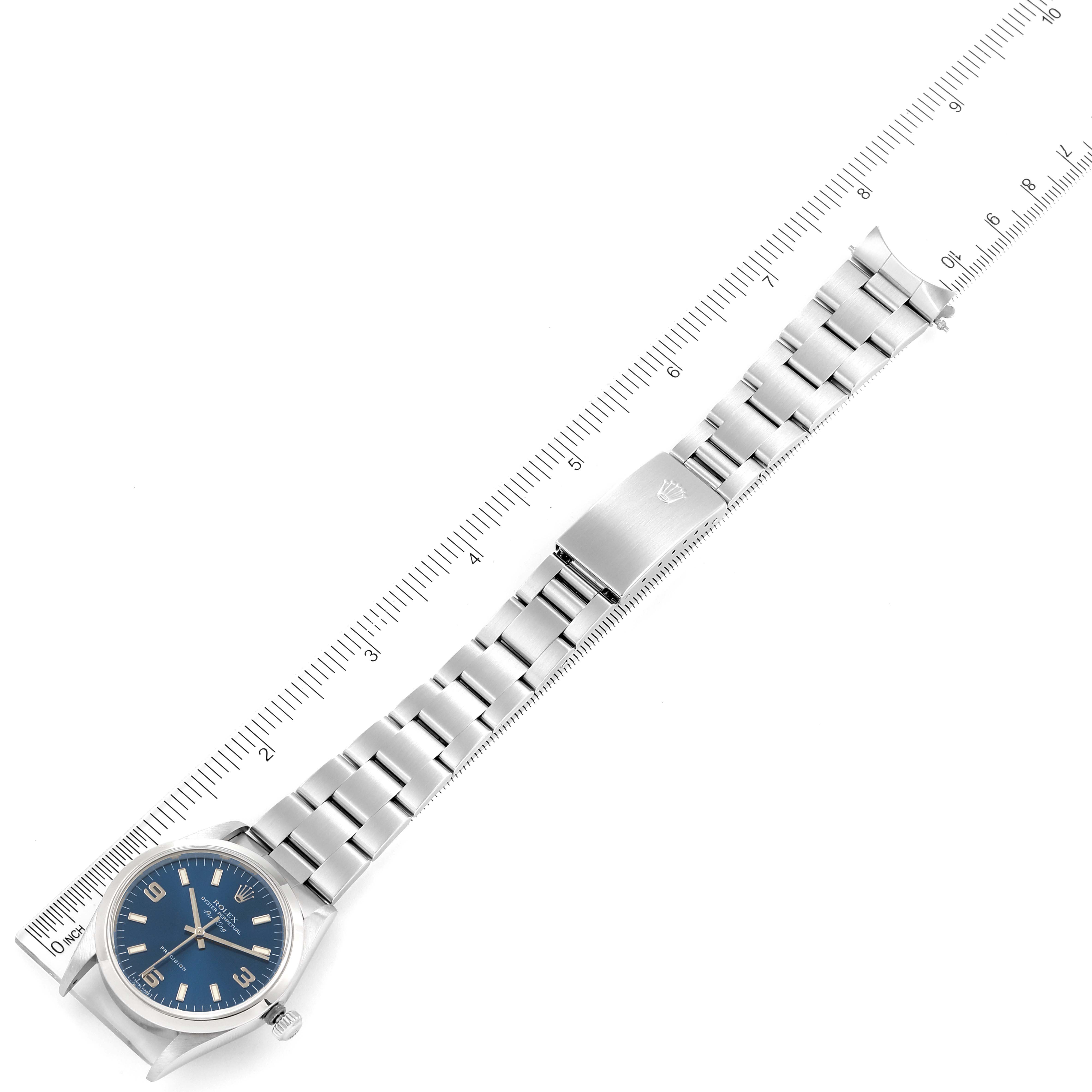 This image shows a top-down view of a Rolex Air-King 14000 Men's Stainless Steel Blue Dial 14000 Men's Stainless Steel Blue Dial watch with its full stainless steel band placed next to a ruler.