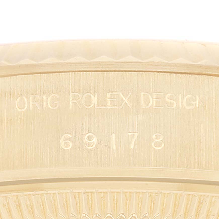 This close-up image shows the engraved serial number and part of the bezel of a Rolex President 69178 Women
s Yellow Gold Champagne Dial 69178 Women
s Yellow Gold Champagne Dial model watch.