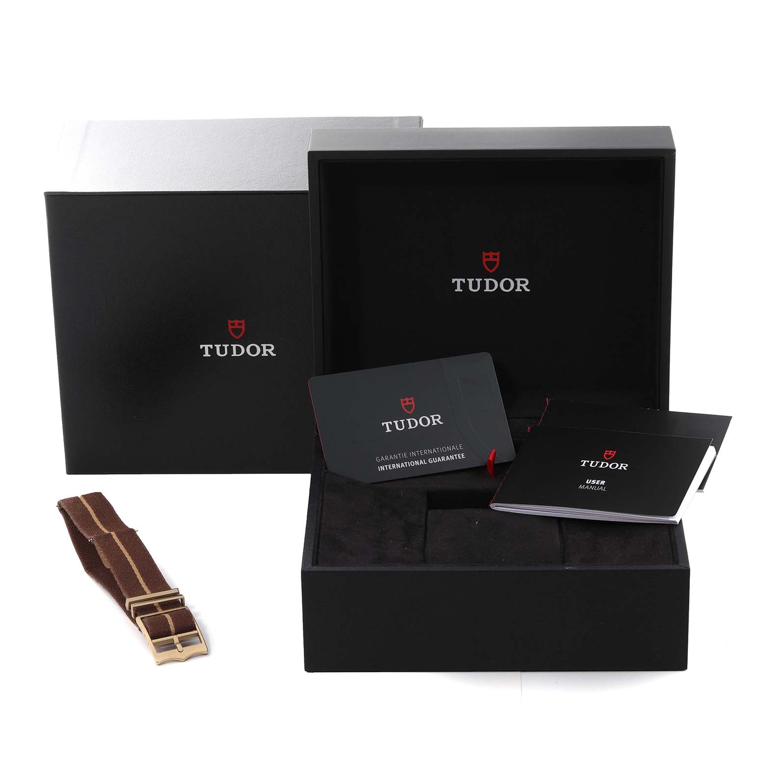 The image shows the packaging and accessories of a Tudor Heritage Black Bay M79012M-0001 Men's Bronze Brown Dial M79012M-0001 Men's Bronze Brown Dial watch, including the box, warranty card, user manual, and an extra strap.