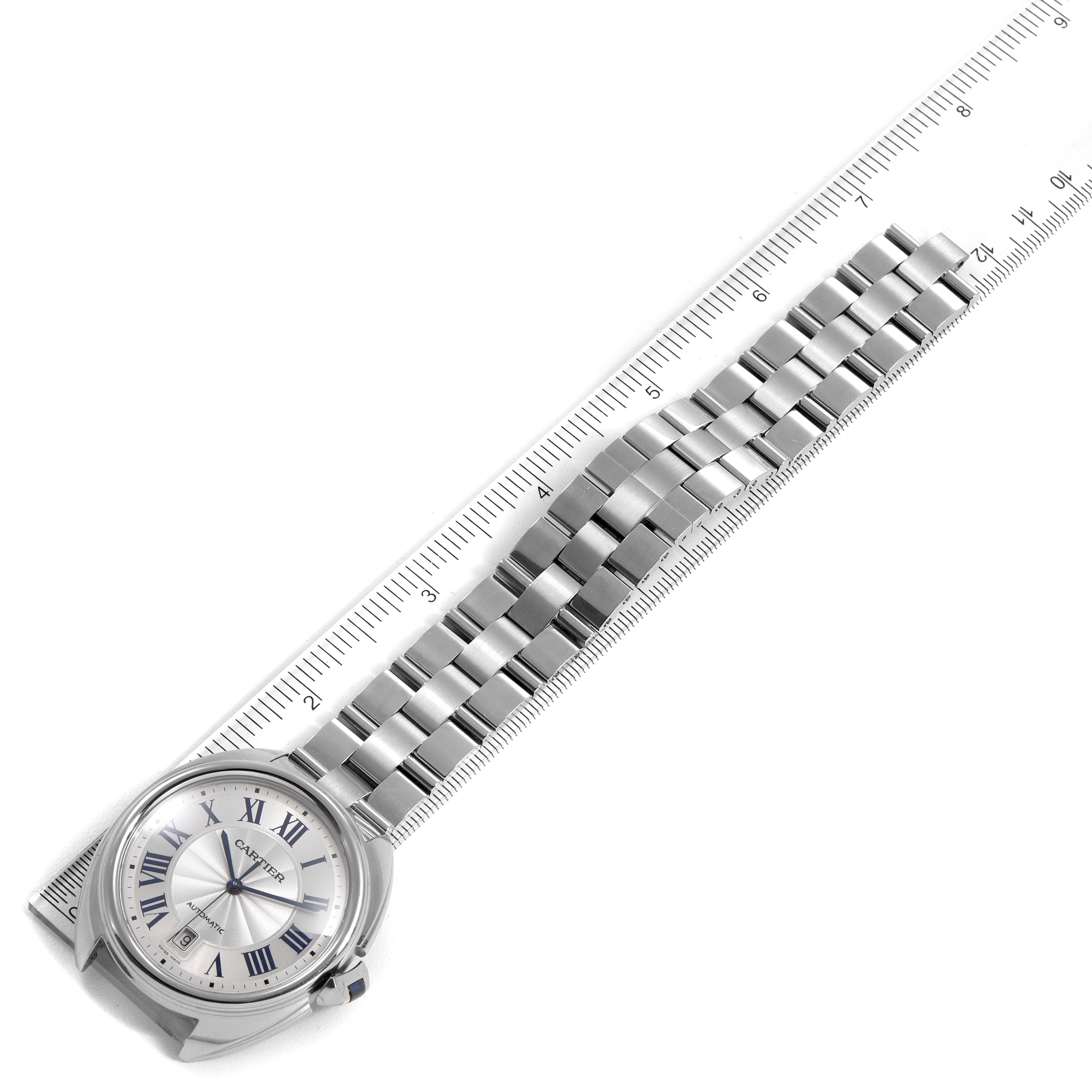 This image shows a top view of the Cartier Cle WSCL0007 Men
s Stainless Steel Silver Dial WSCL0007 Men
s Stainless Steel Silver Dial model watch and its metal bracelet alongside a ruler for measurement.
