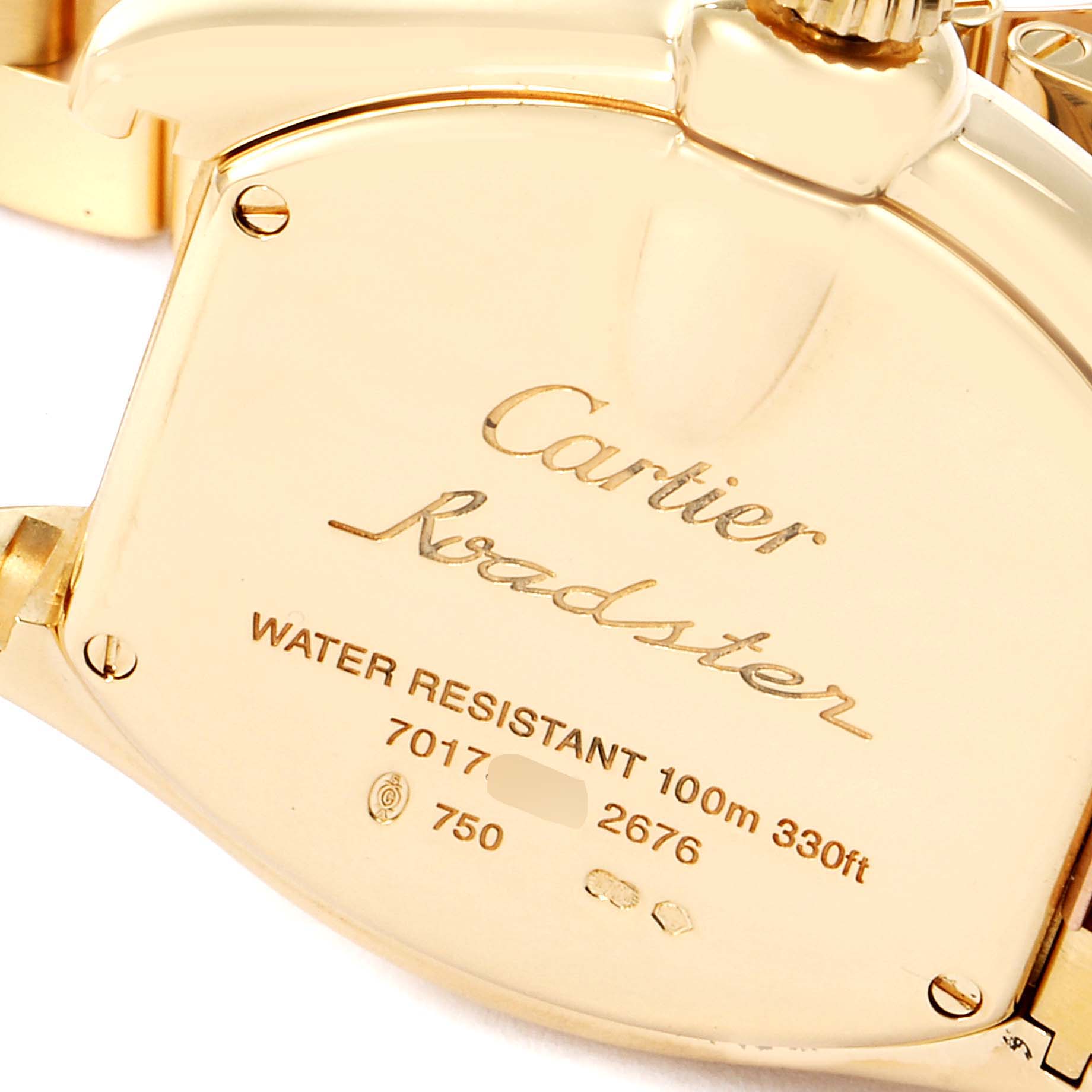 The image shows the back case and crown of a Cartier Roadster W62018V1 Women's Yellow Gold Silver Dial W62018V1 Women's Yellow Gold Silver Dial watch, highlighting its gold finish and engravings.