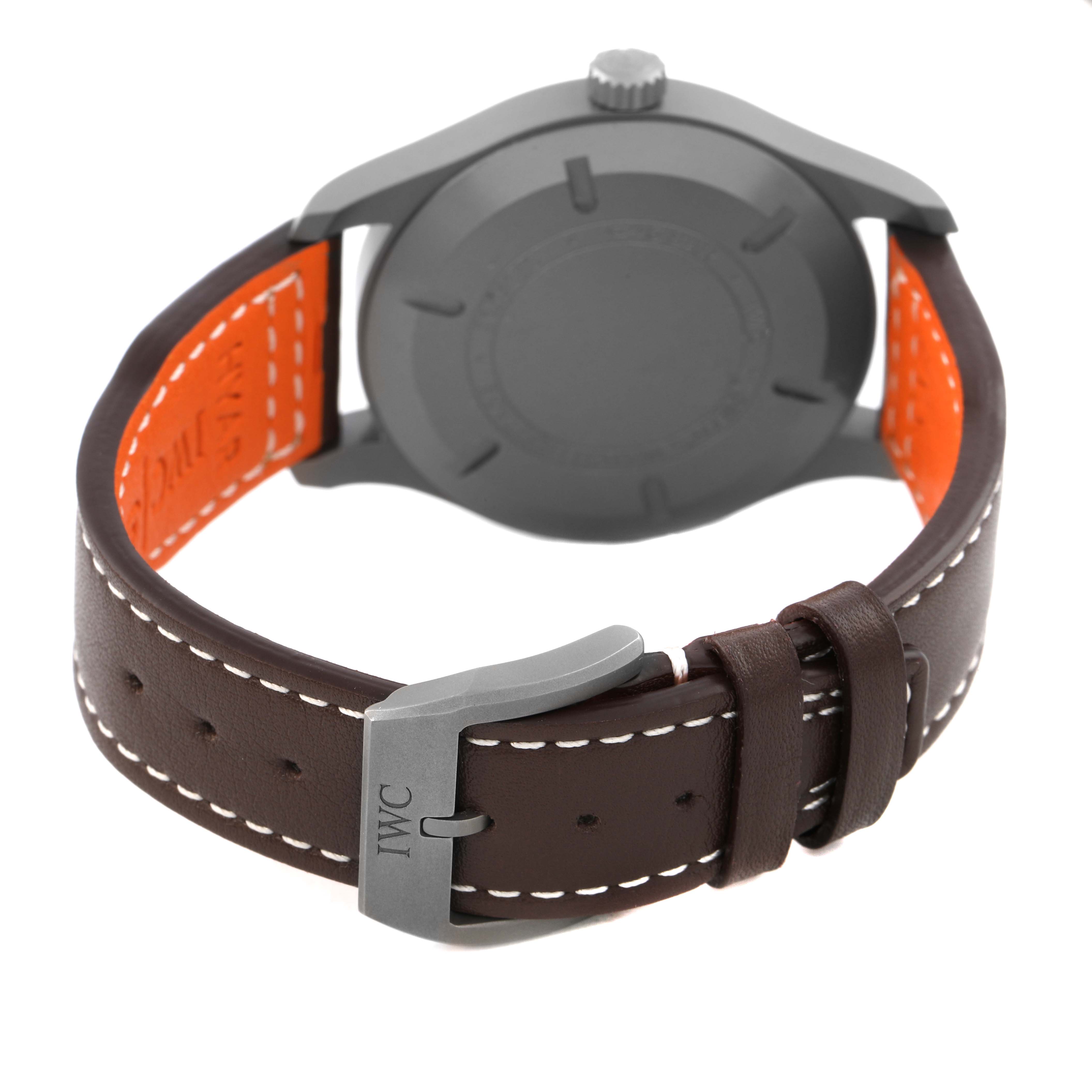 The image shows the back of an IWC Pilot IW327006 Men's Titanium Black Dial model watch with its case back, crown, and brown leather strap featuring white stitching.