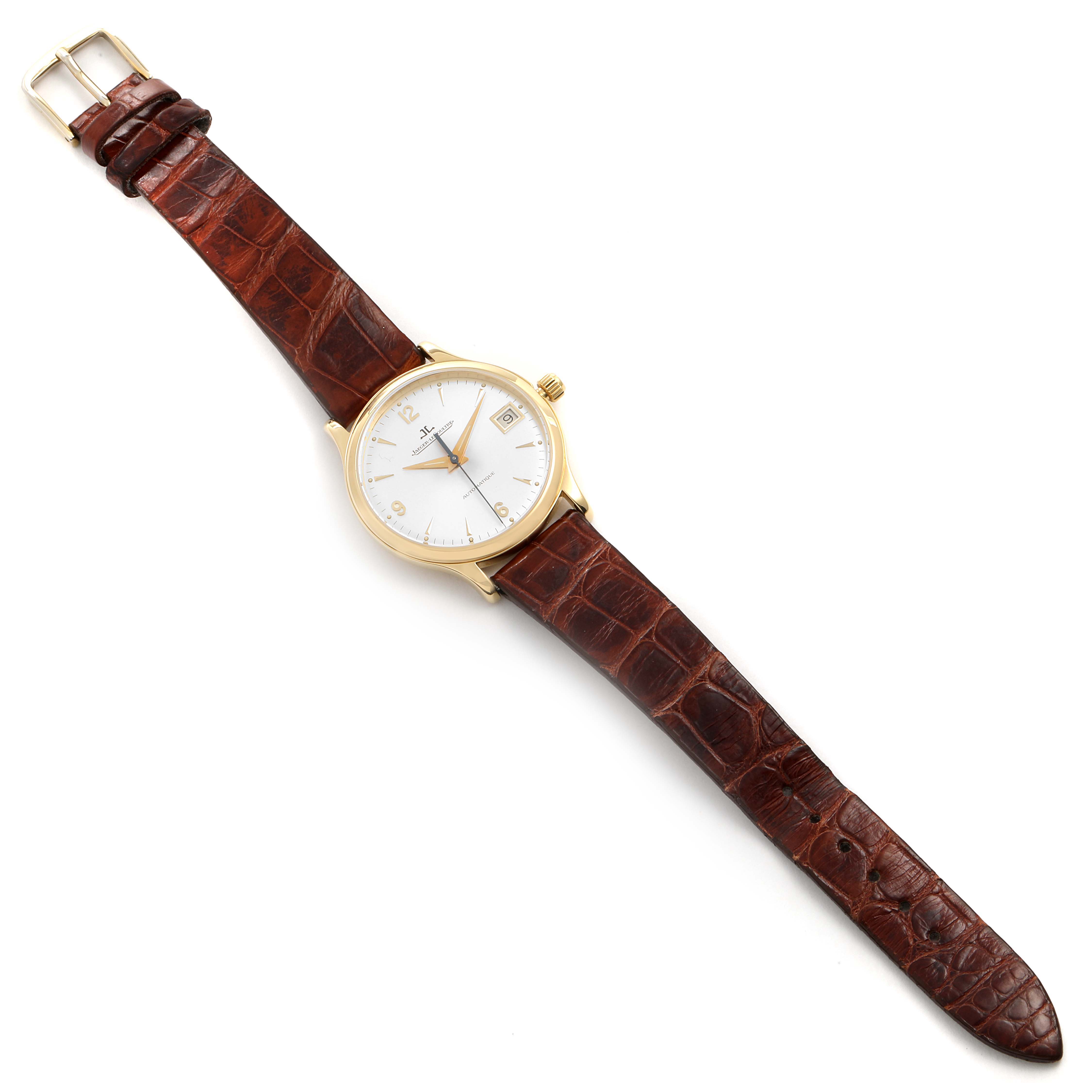 The image shows a Jaeger-LeCoultre Master watch from an above angle, displaying its round gold case, white dial, brown leather strap, and buckle.