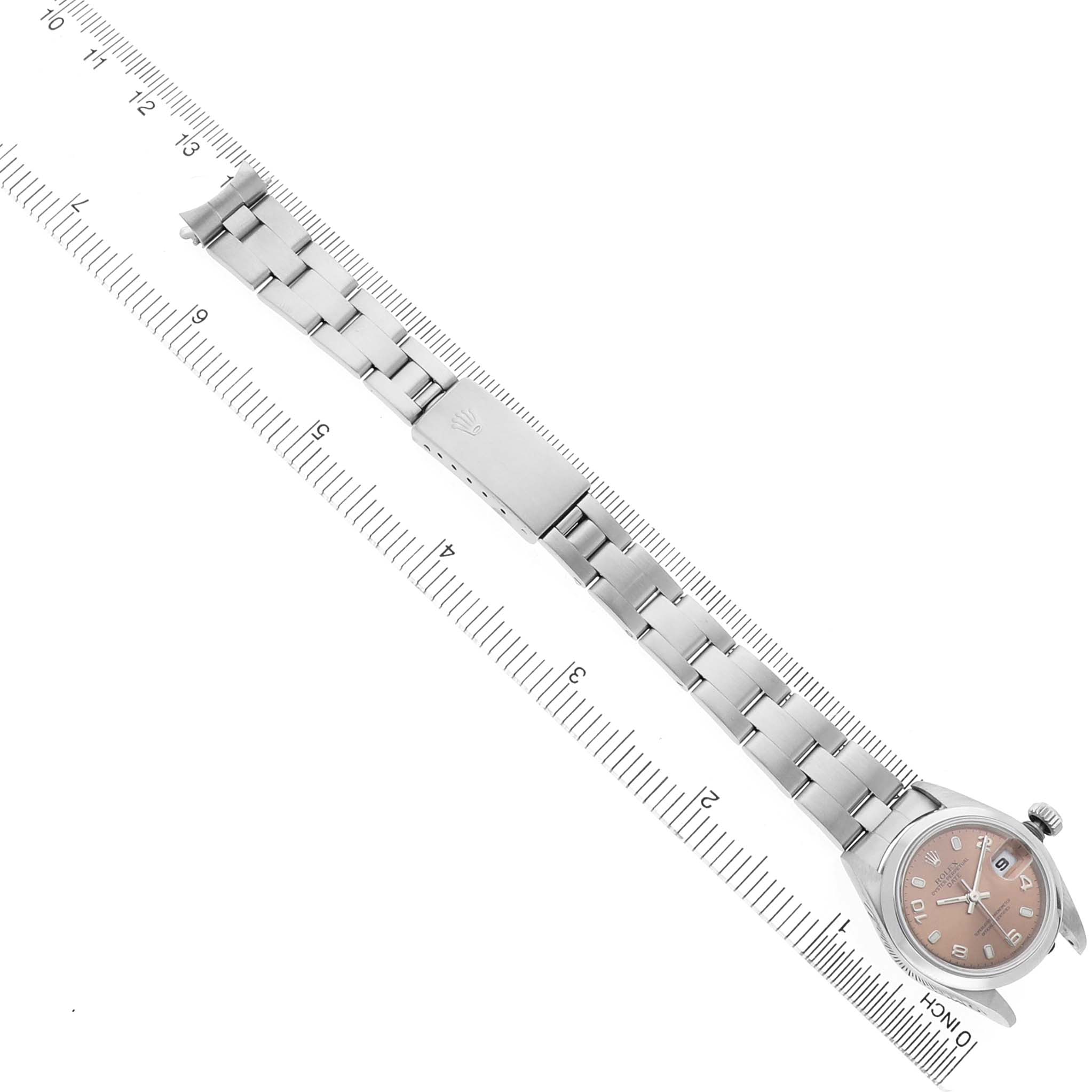 The Rolex Date 79160 Women's Stainless Steel Pink Dial watch is shown from a top-down angle, with its entire bracelet and face visible, alongside a measurement ruler.