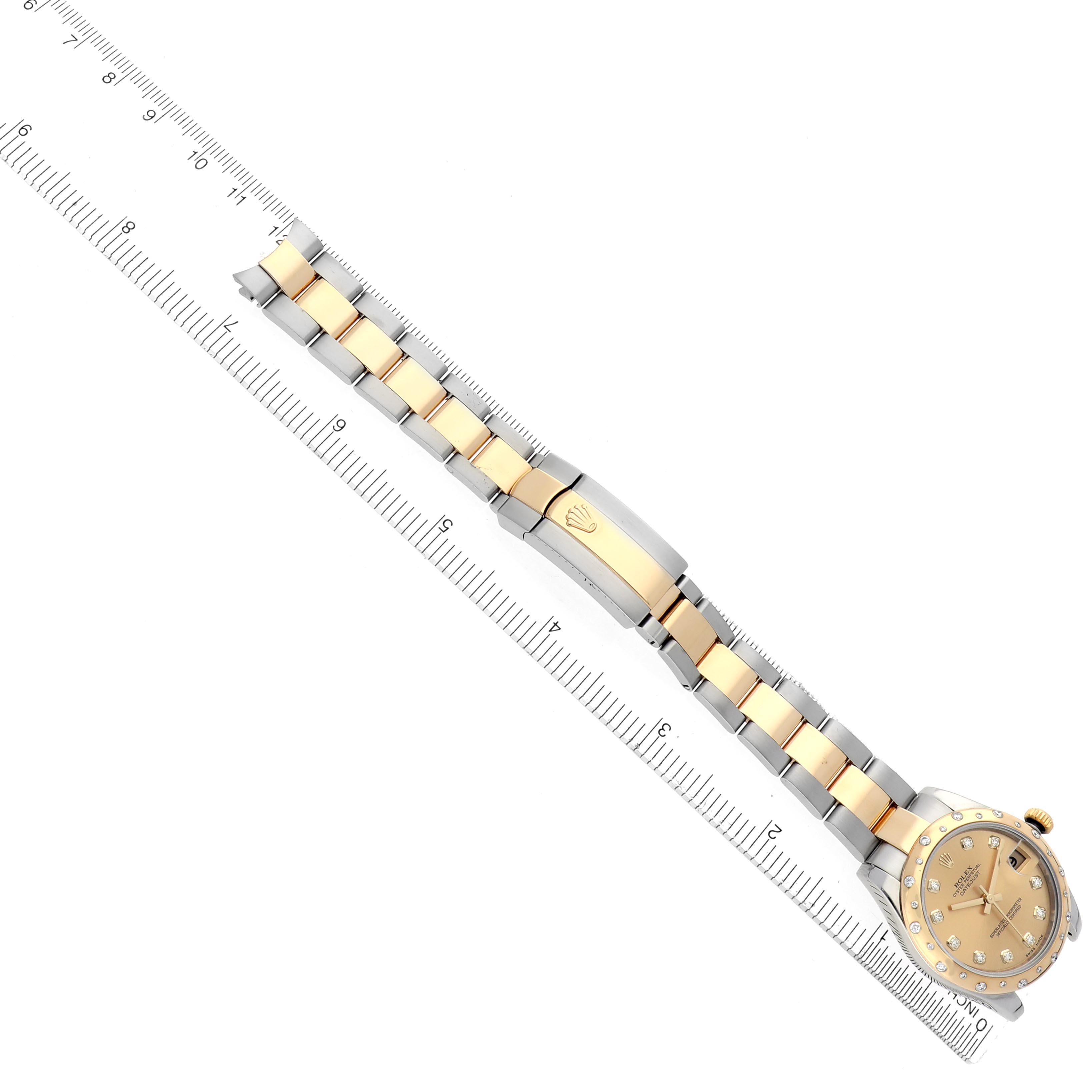 The Rolex Mid-Size 278343 Women's Steel and Gold (two tone) Champagne Dial 278343 Women's Steel and Gold (two tone) Champagne Dial watch is shown from a top-down angle, displaying the face, bracelet, and clasp alongside a ruler.